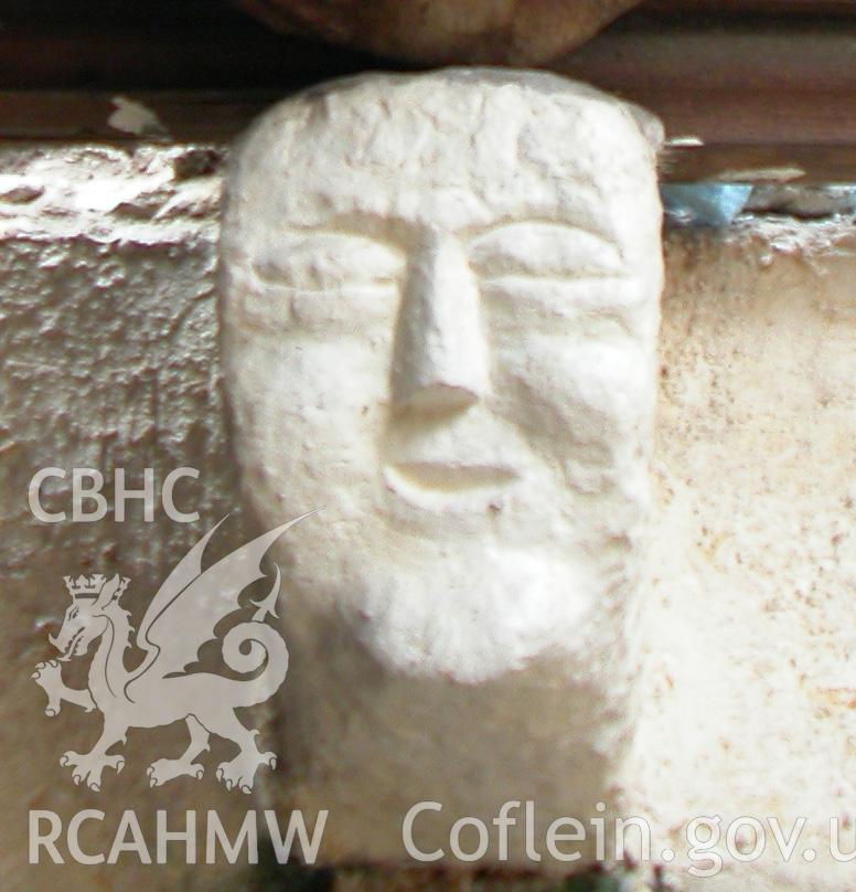 Carved stone head between Trusses II & III, south side.