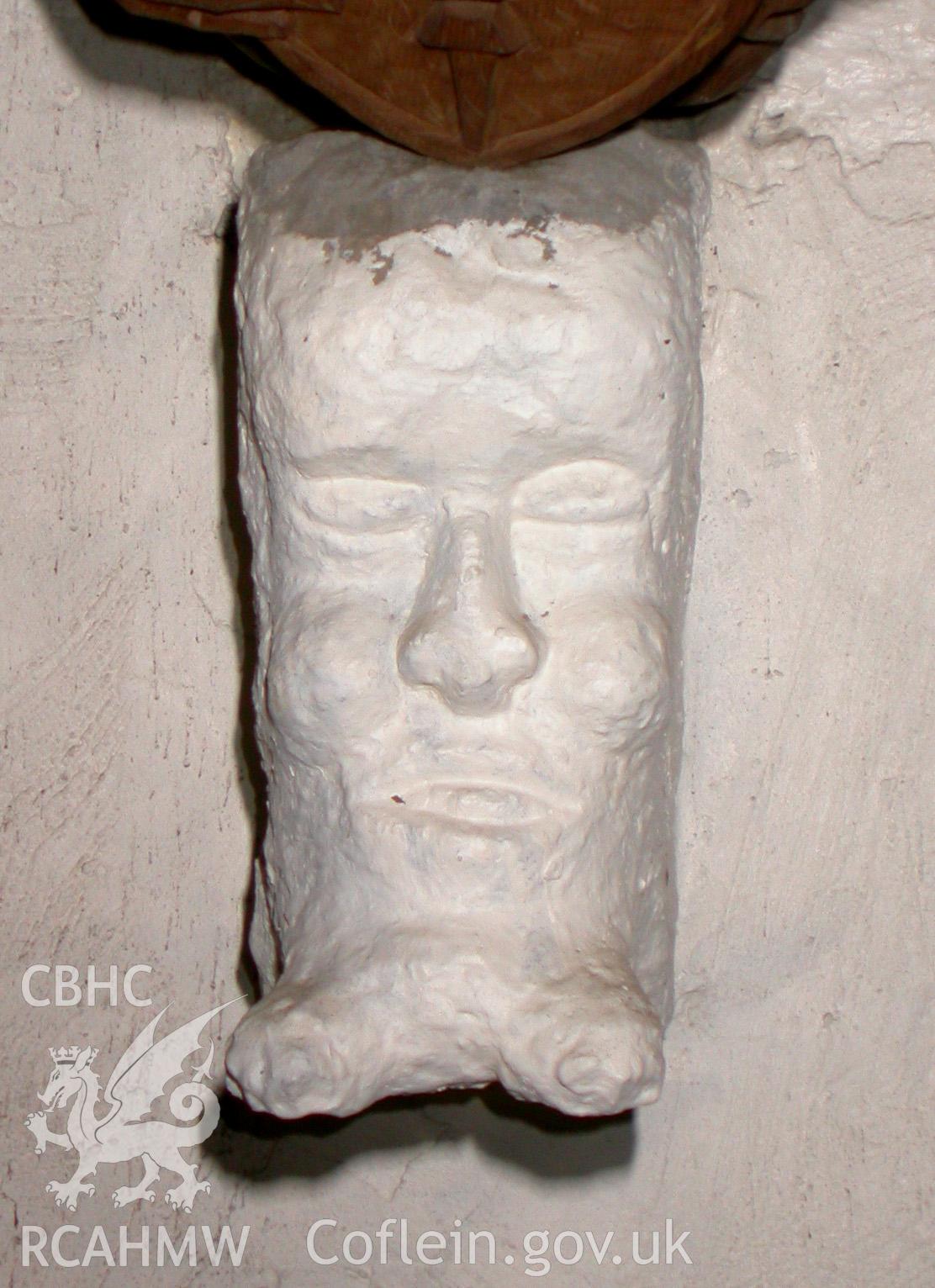 Carved stone head at east end, to south.