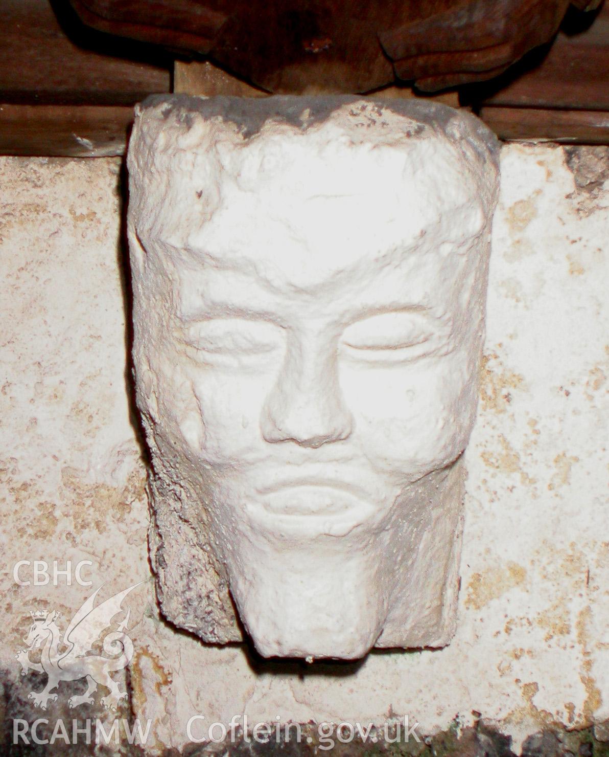 Carved stone head between Trusses V & VI, south side.