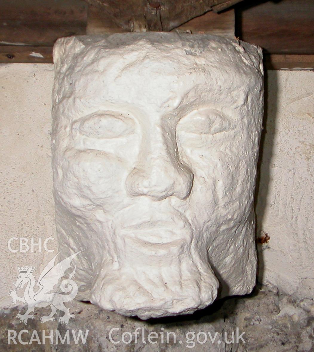 Carved stone head between Trusses V & VI, north side.