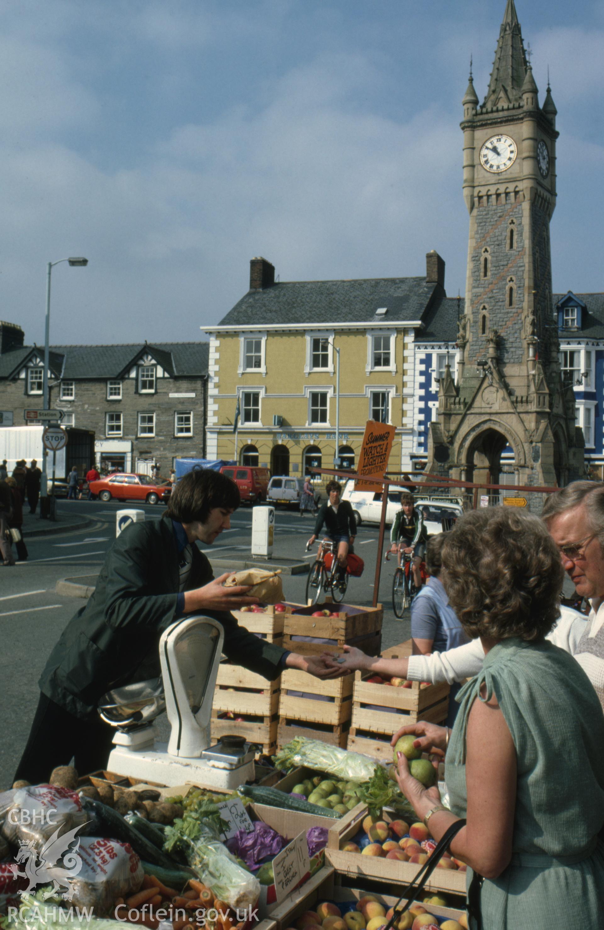 Colour photographic transparency showing view of Machynlleth town with stalls on market day; collated by the former Central Office of Information.