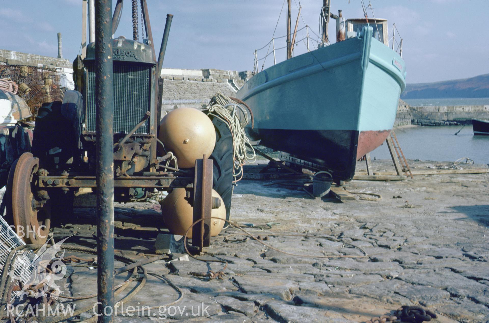 Colour 35mm slide showing a tractor and boat at New Quay Harbour, Ceredigion, by Dylan Roberts.