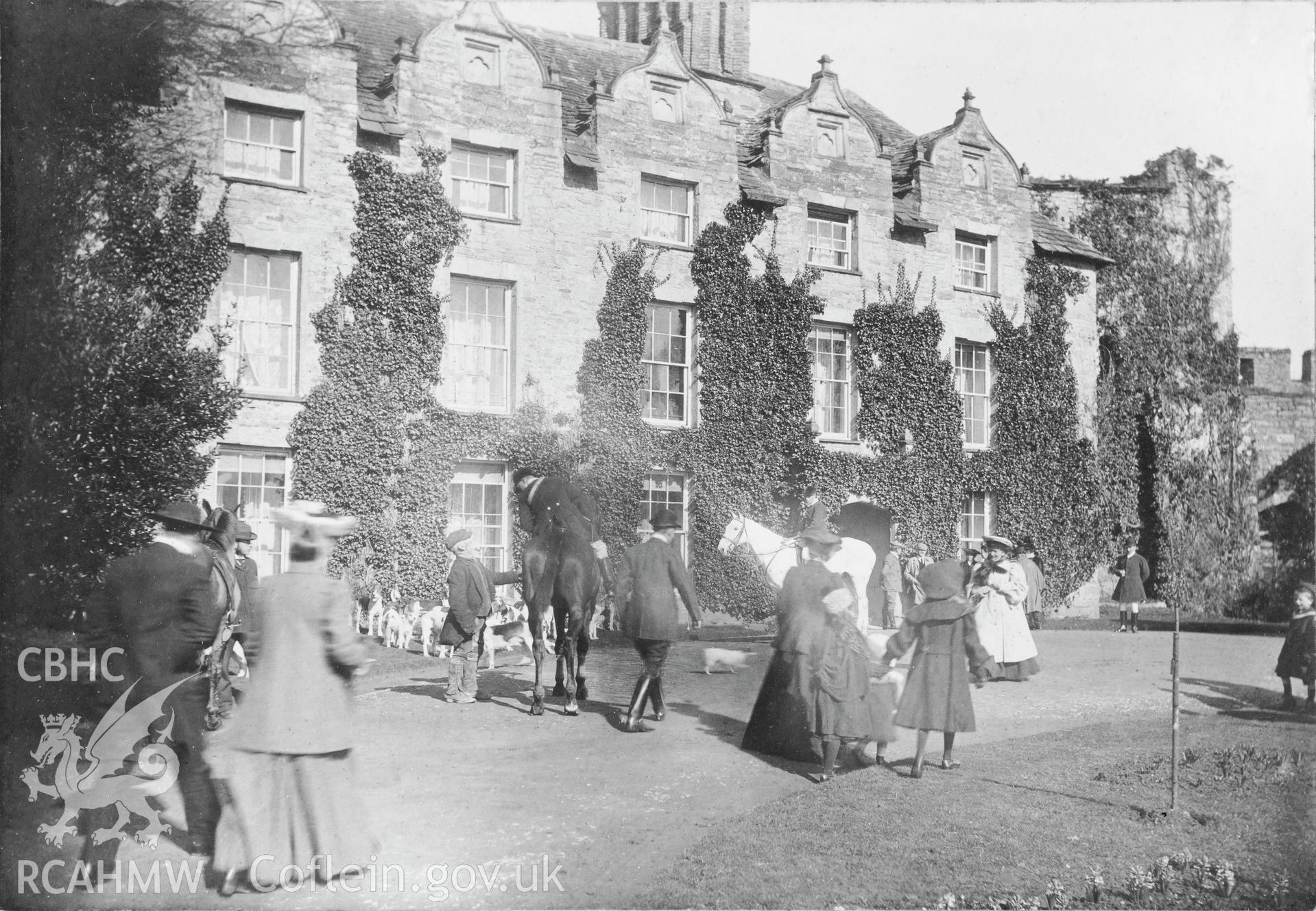 Vintage image of front entrance with fox hounds, and guests.