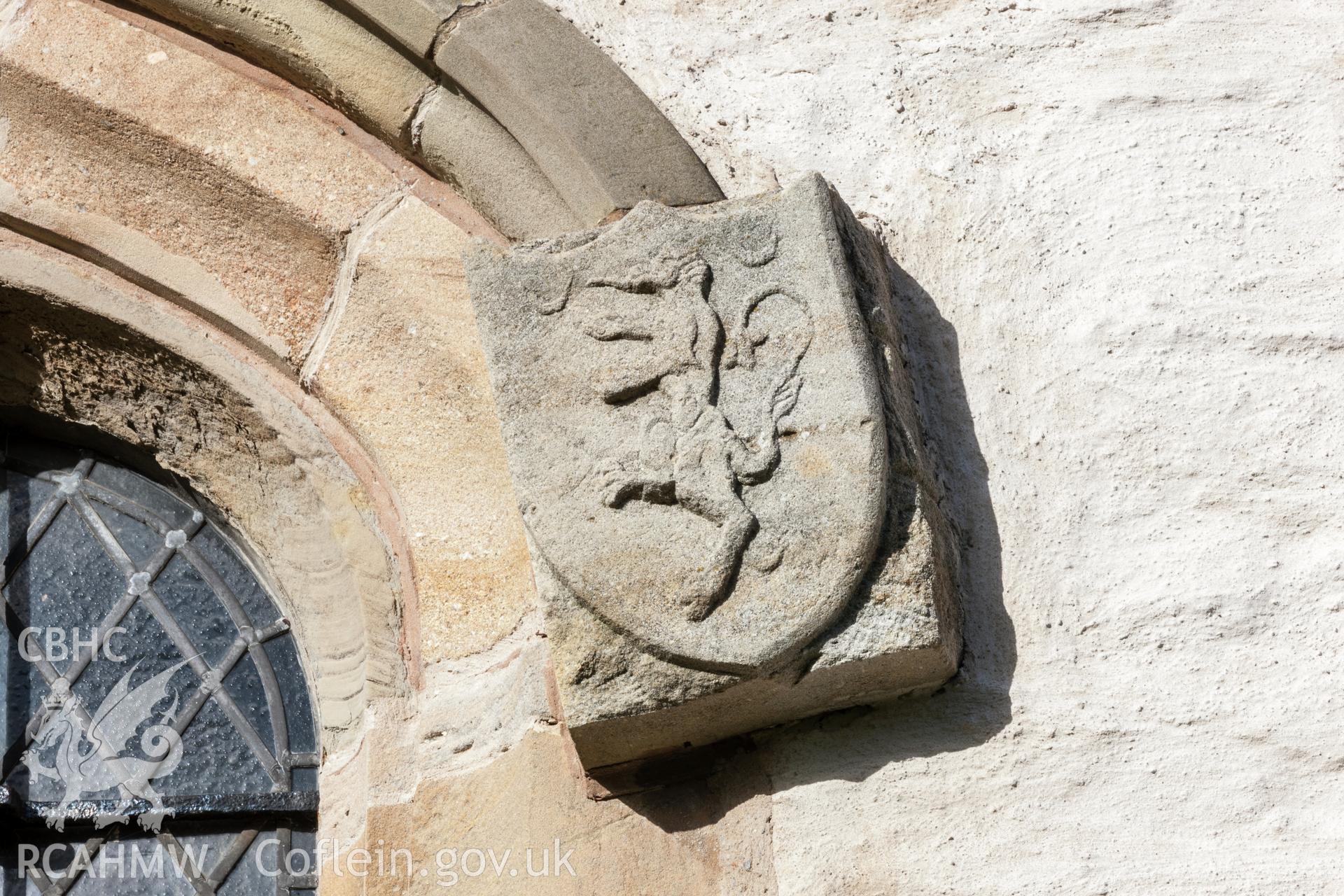 Carved stone crest on window arch, southwall