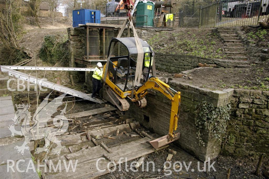 Digital image relating to Melingriffith Water Pump: Mini excavator being lowered into wheel pit to assist with removal of accumulated silt and debris.