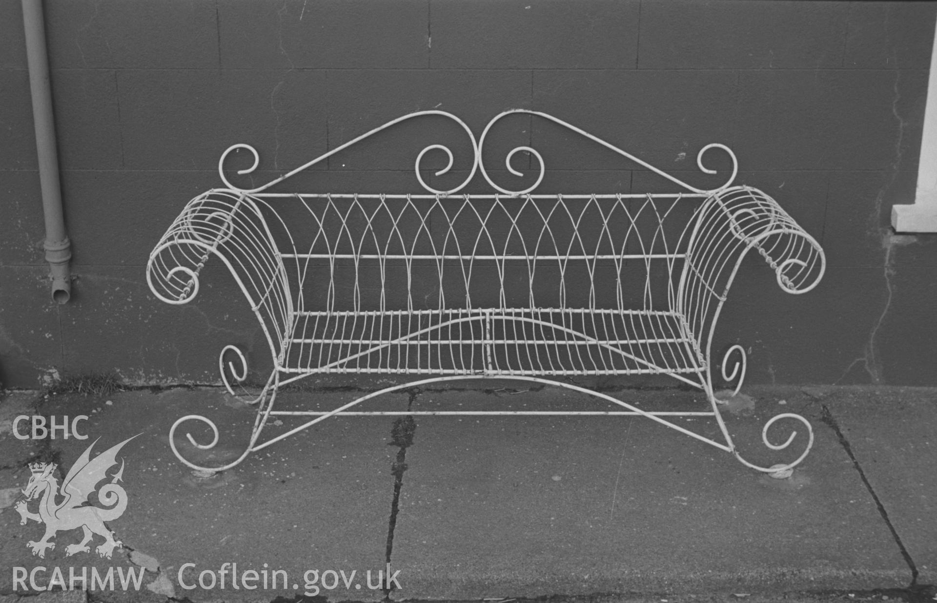 Black and White photograph showing iron bench at Aberaeron. 'Iron seat outside house on the north side of the lower harbour in quay Parade.' Photographed by Arthur Chater, February 1963. Grid ref: SN 4561 6295, looking north east.