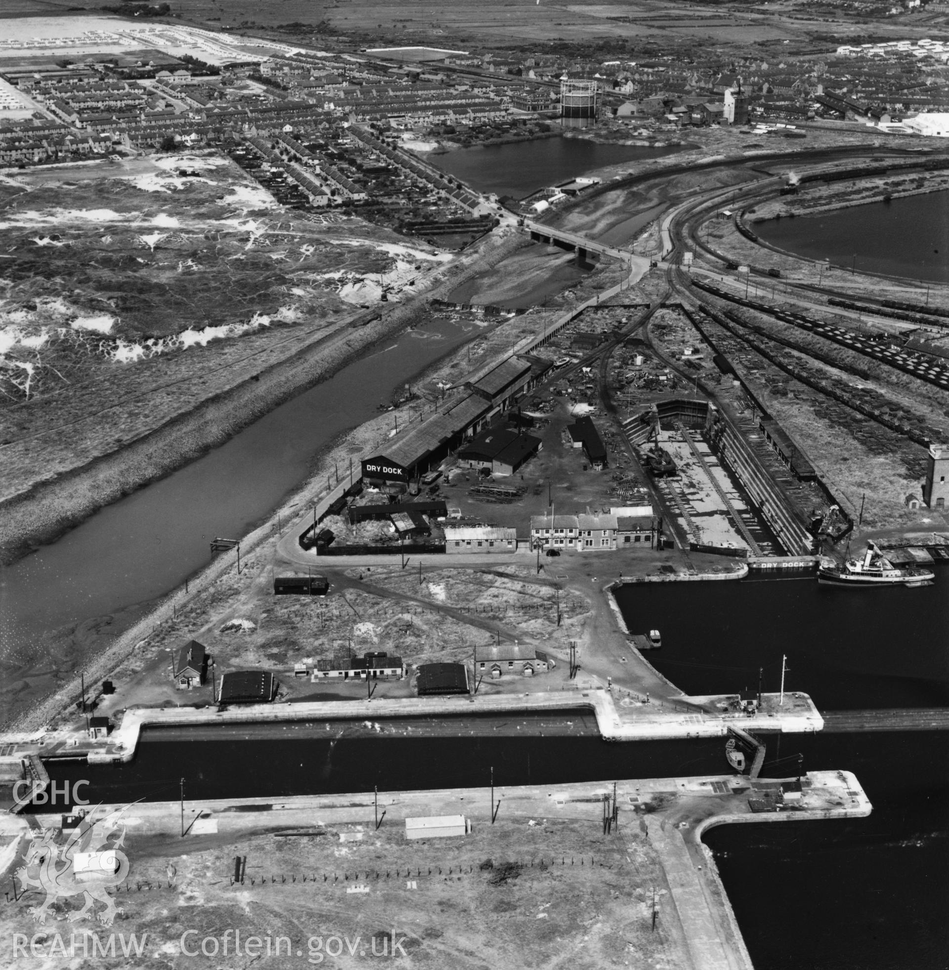 View of dry, new and old docks and entrance channel, Port Talbot, with Sandfields estate in background. Oblique aerial photograph, 5?" cut roll film.