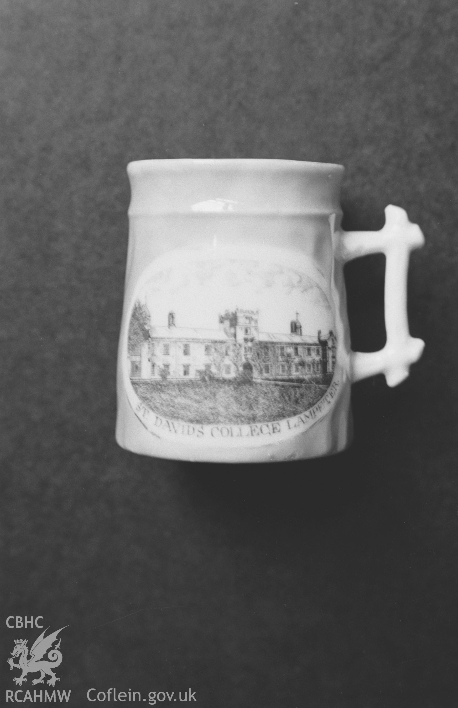 Digital copy of a black and white negative showing a china mug depicting St David's college, Lampeter. Photographed by Arthur O. Chater in January 1968.