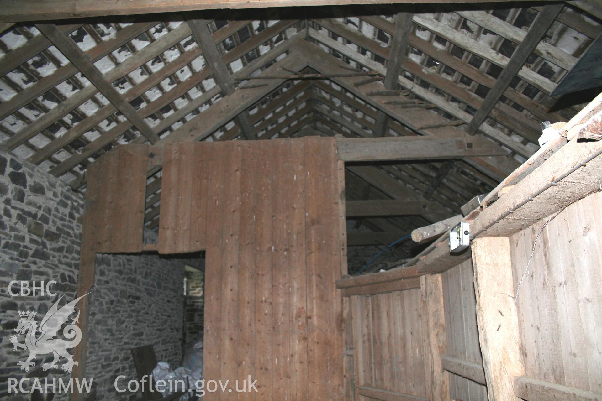 Interior view of stone walls, wooden roof beams and wooden partitions.Photographic survey of the northern range of cattle-shelters at Tan-y-Graig Farm, Llanfarian, conducted by Geoff Ward and John Wiles, 11th December 2006.