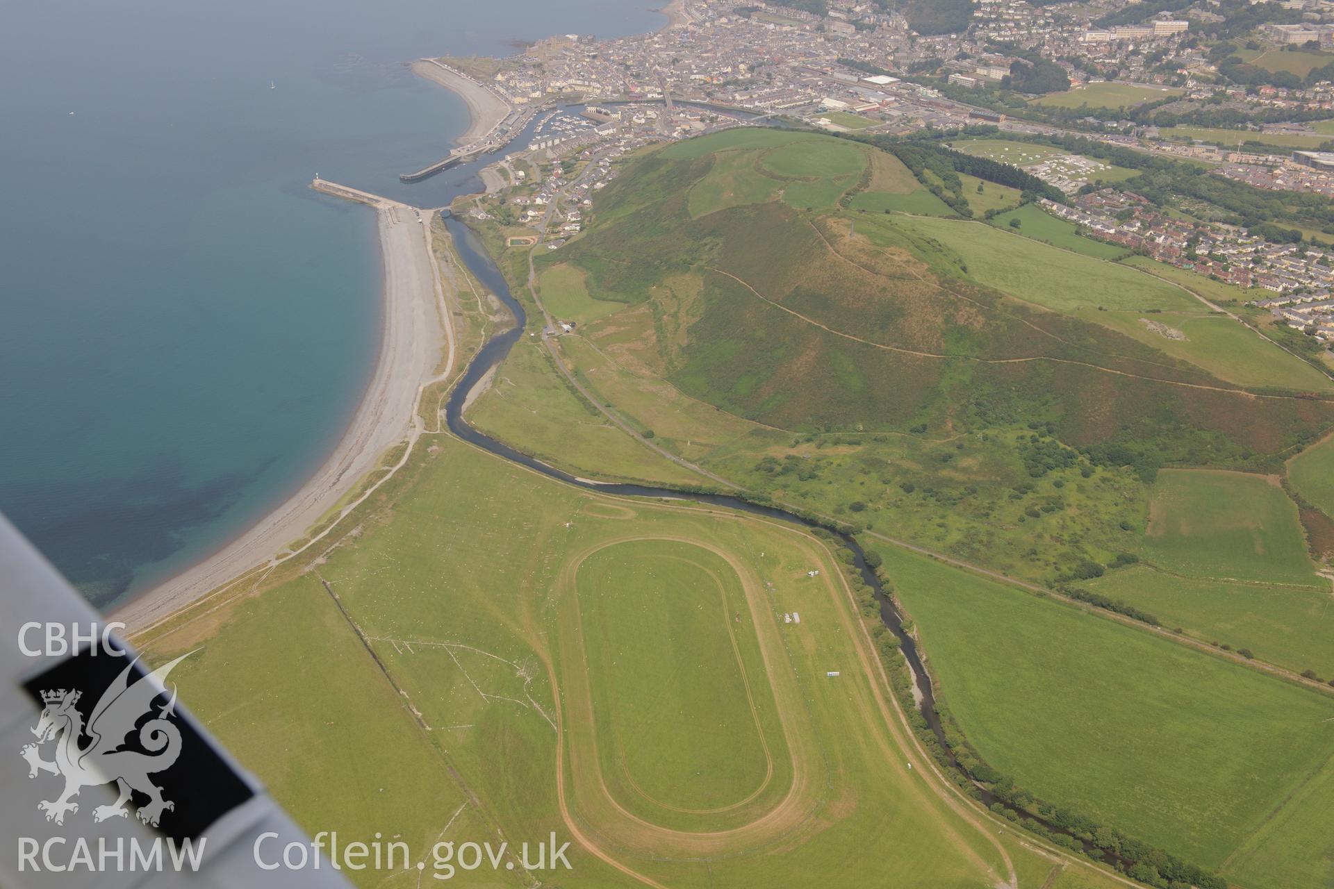 Ceredigion Trotting Circuit at Tan y Castell, with Pendinas hillfort and the town of Aberystwyth beyond. Oblique aerial photograph taken during the Royal Commission?s programme of archaeological aerial reconnaissance by Toby Driver on 12th July 2013.