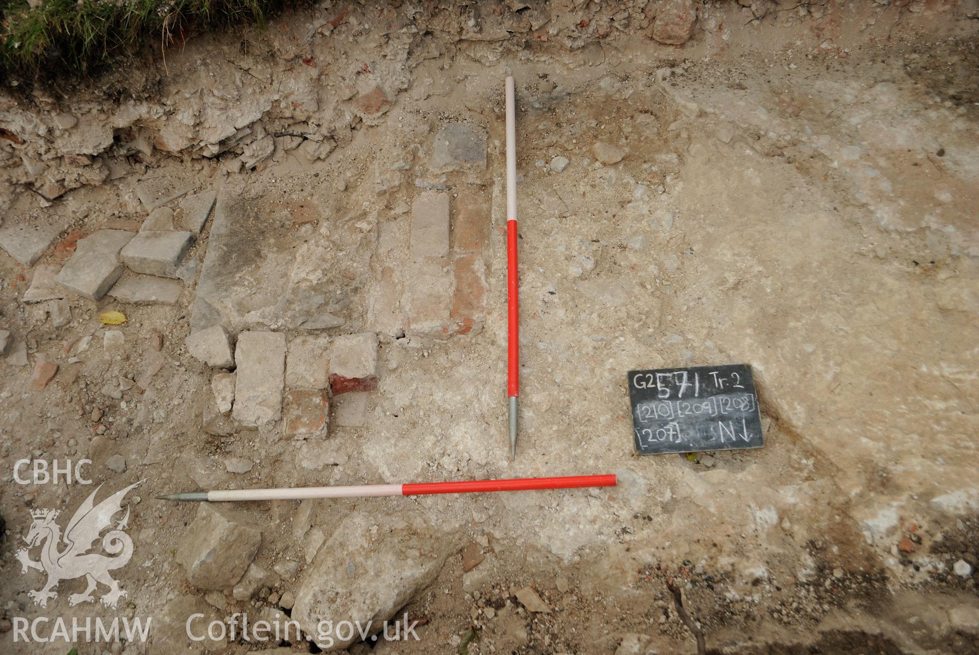 View from north of mortar deposit; stone deposit; brick linear feature and rectangular slab. Photographed during archaeological evaluation of Kinmel Park, Abergele, by Gwynedd Archaeological Trust on 24th August 2018. Project no. 2571.