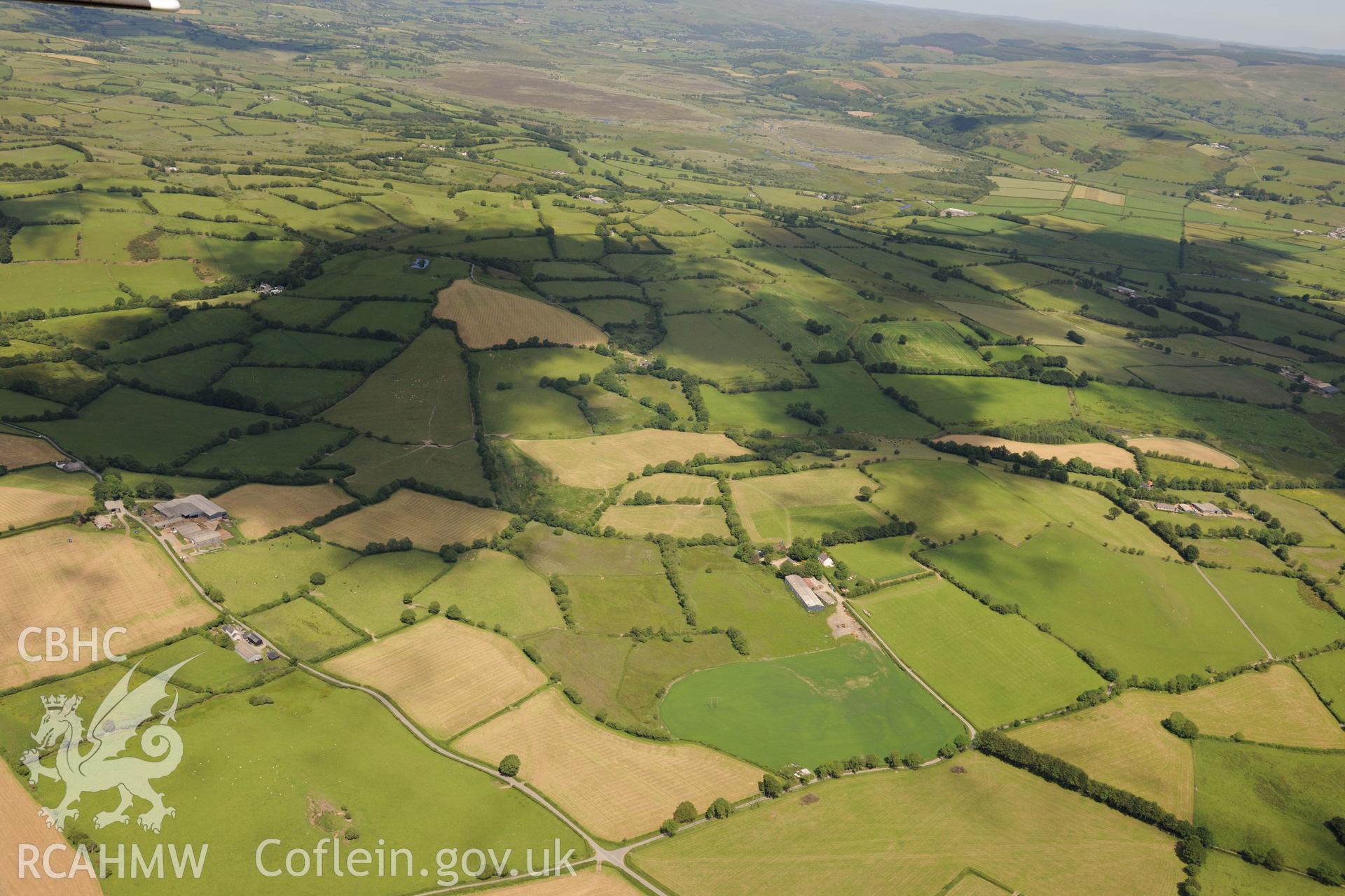 Deri Odwyn, a possible early field system at Deri Odwyn and Llwynpiod chapel in the distance (left hand corner of the photograph). Oblique aerial photograph taken during the Royal Commission's programme of archaeological aerial reconnaissance by Toby Driver on 30th June 2015.
