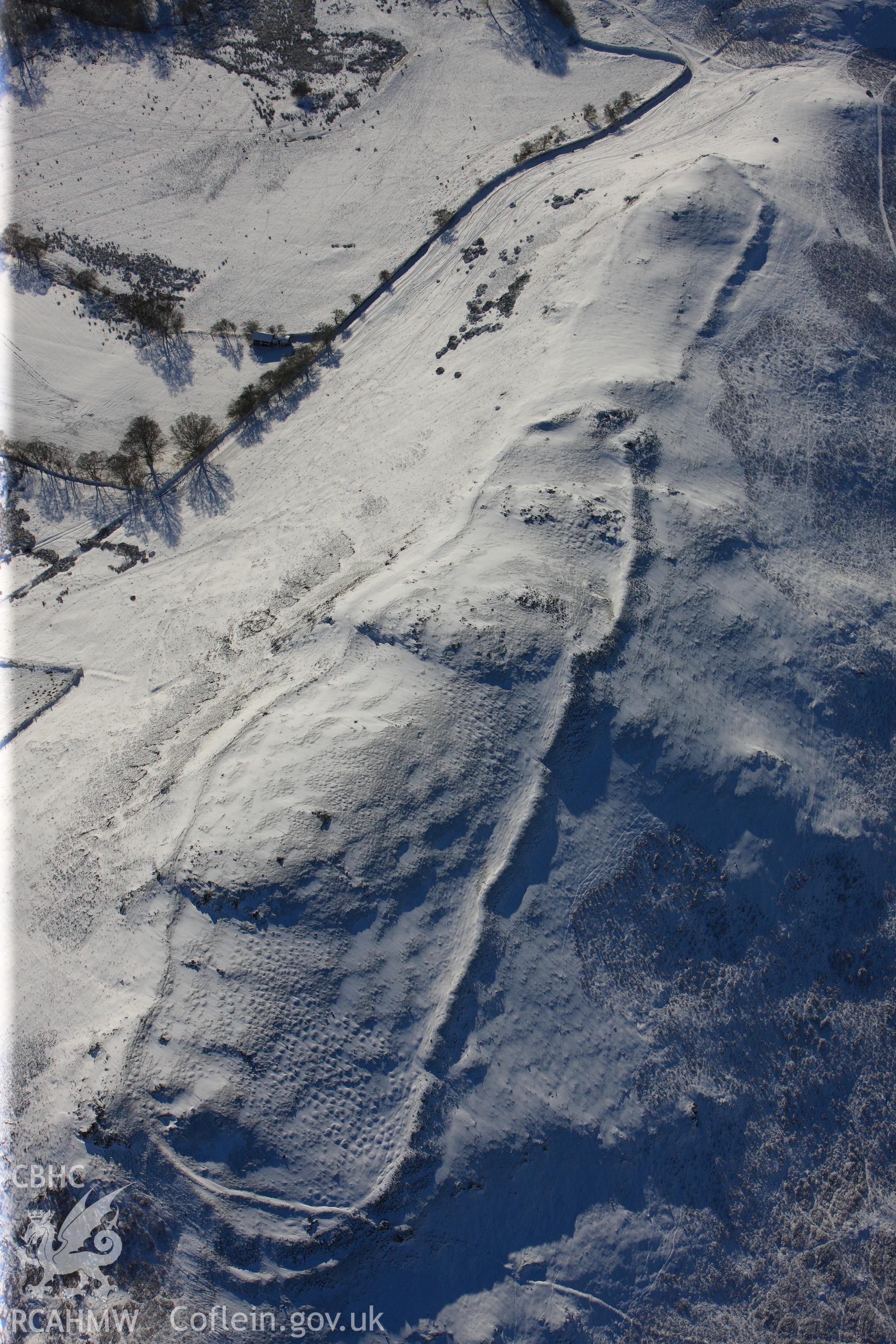 Castle Bank hillfort under snow, north east of Builth Wells. Oblique aerial photograph taken during the Royal Commission?s programme of archaeological aerial reconnaissance by Toby Driver on 15th January 2013.