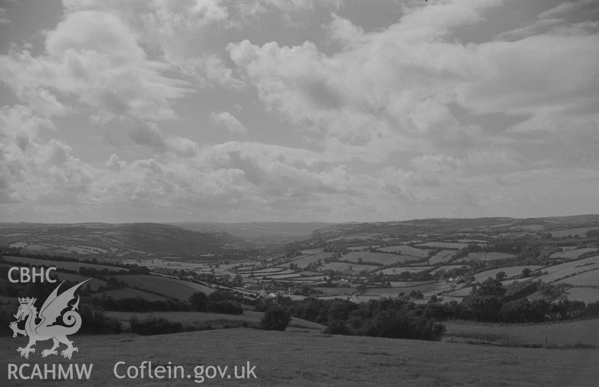 Digital copy of black and white negative showing view of Llangeitho and the Aeron valley from bank of lane at bottom of Llanbadarn-Odwyn churchyard. Photographed by Arthur O. Chater on 2nd September 1967 looking south west from Grid Ref SN 634 605.