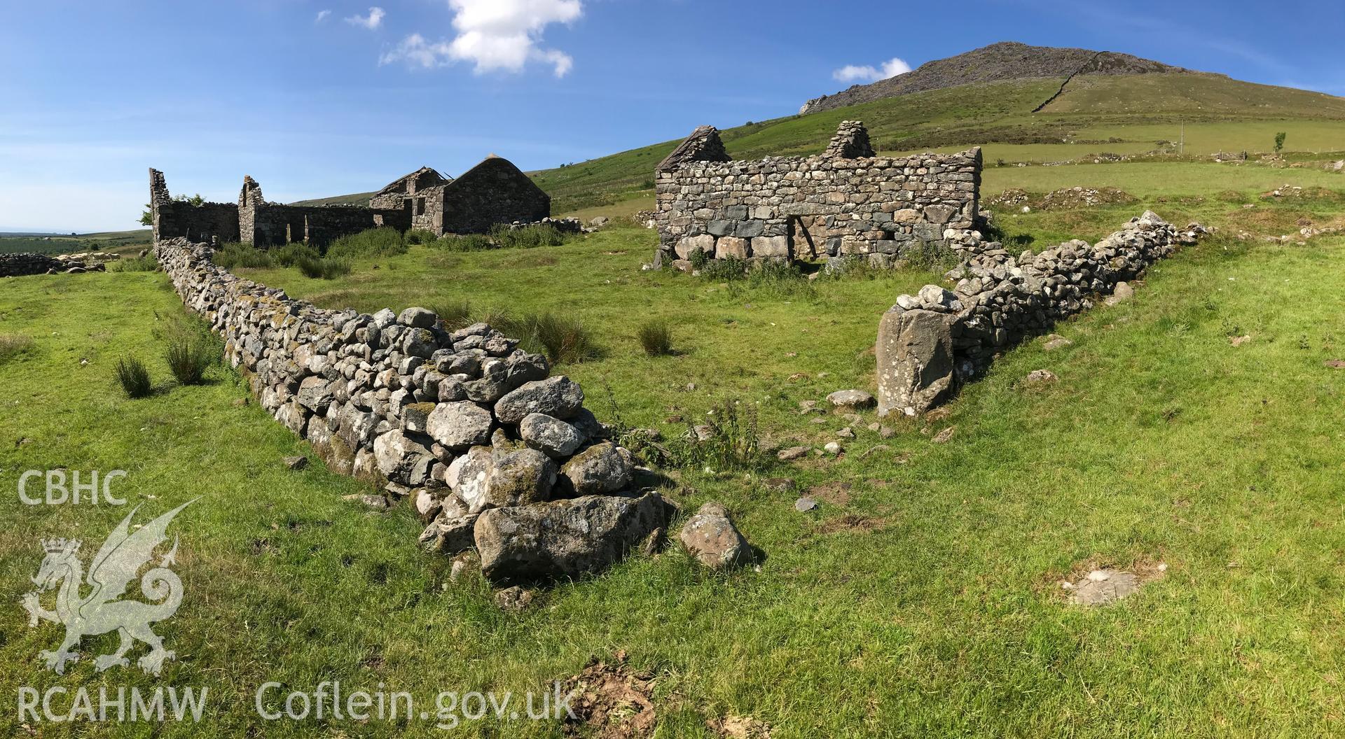 Colour photo showing view of drystone walls, remnants of possible outbuildings and Cae-Mwynen house, Clynnog, taken by Paul R. Davis, 24th June 2018.