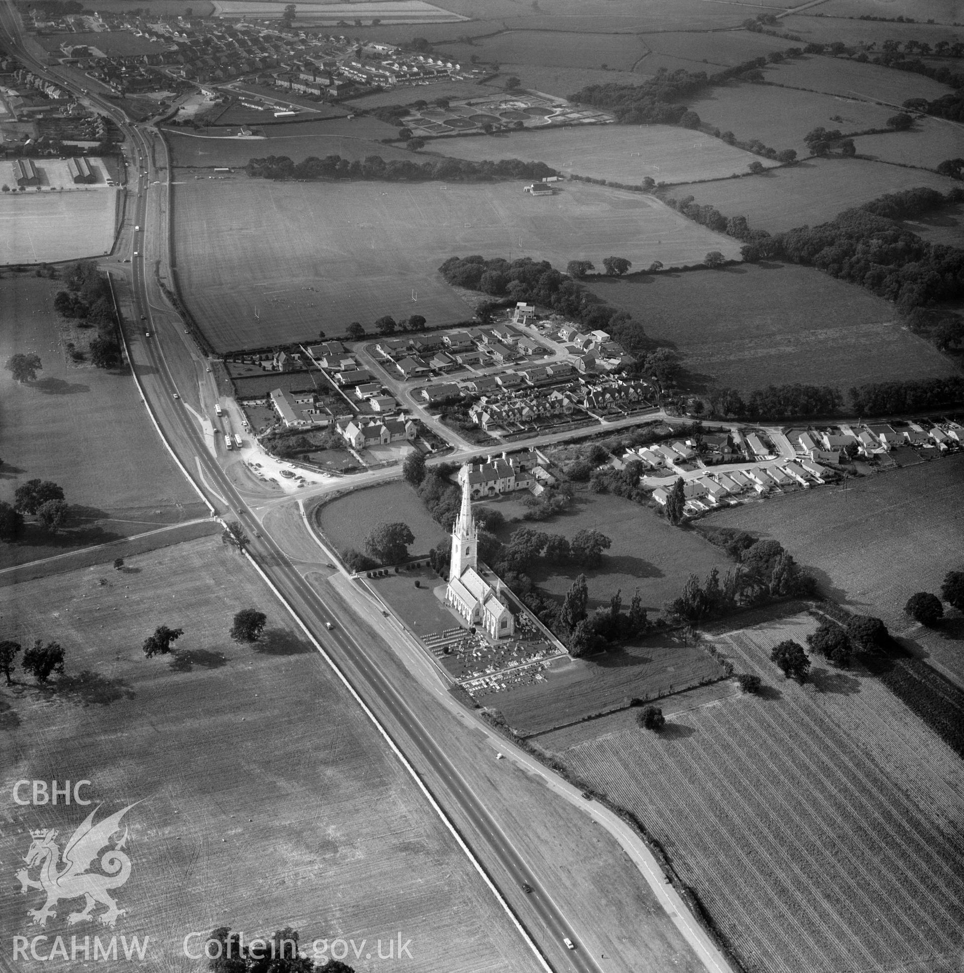Digital copy of a black and white, oblique aerial photograph of the Marble Church, Bodelwyddan. The photograph shows a view from the South East. The serried gravestones of the Canadian soldiers killed in the 1919 riot at nearby Kinmel Military Camp are clearly visible in the Churchyard.
