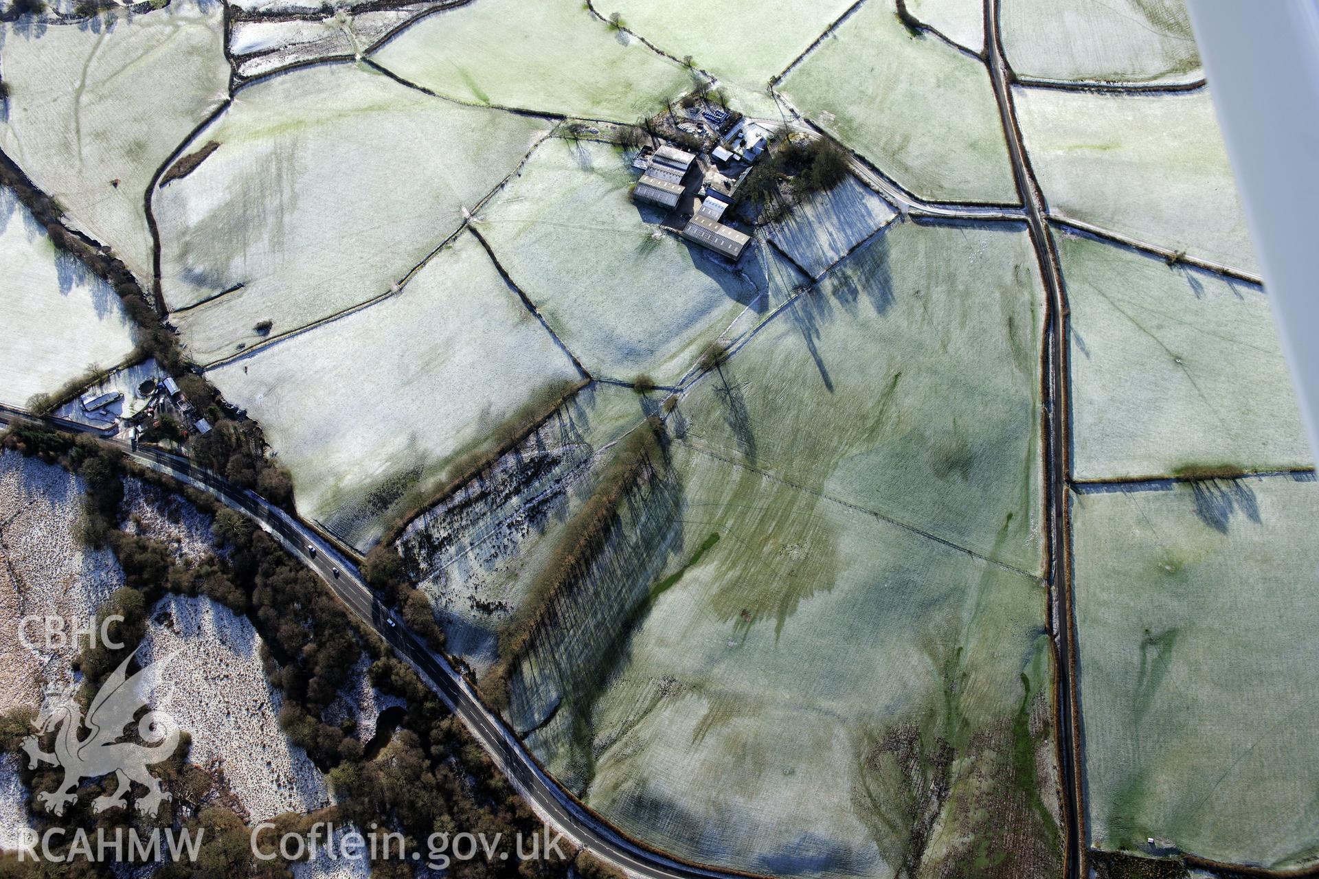 Twdin or Caerau Motte, Caerau Roman fort and military settlement, and the Roman road from Carmarthen to Castell Collen (RR623). Oblique aerial photograph taken during the RCAHMW?s programme of archaeological aerial reconnaissance by Toby Driver 15/01/2013.