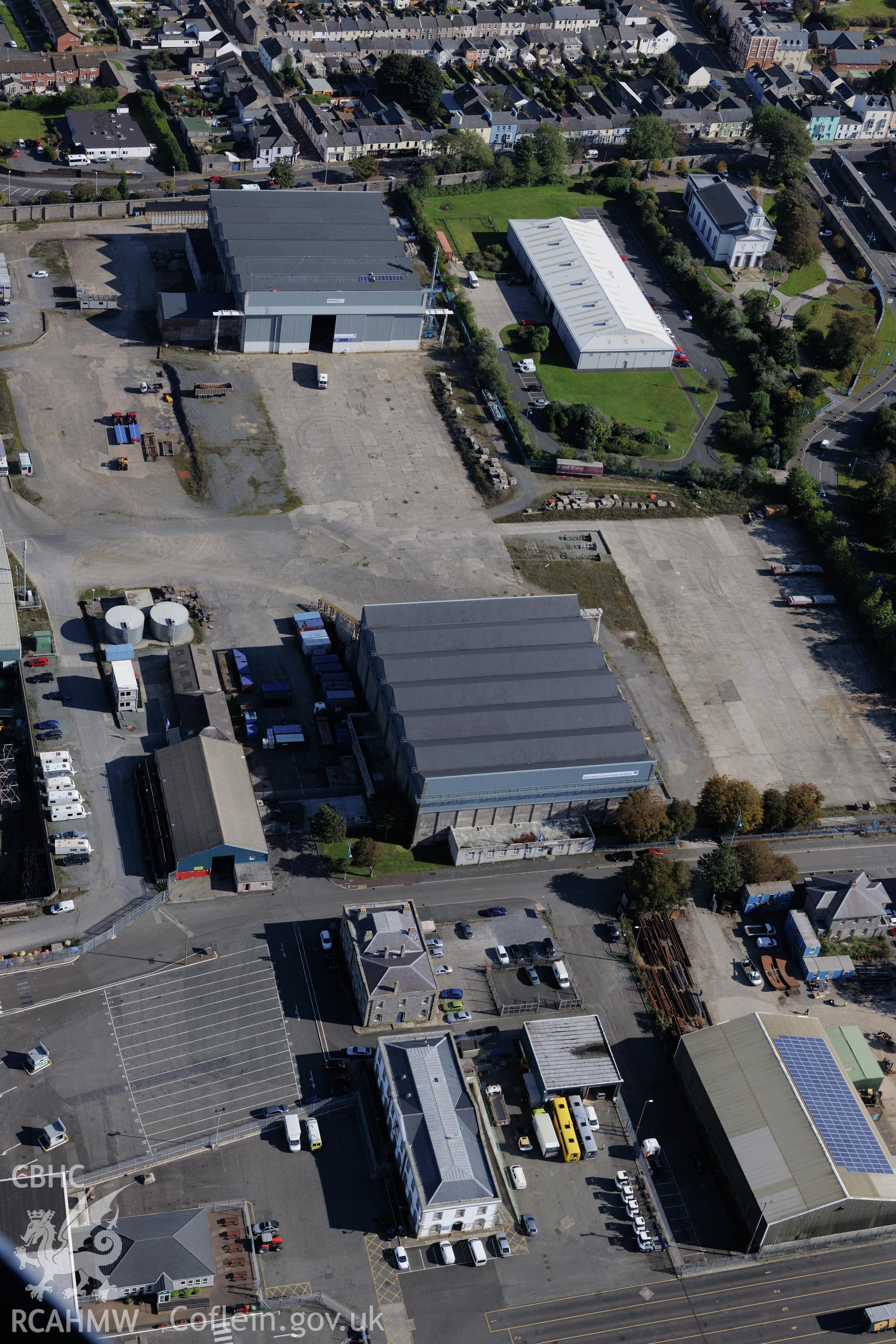 Pembroke Dockyard including the storehouse, motor museum, office block and the east and west hangars of the flying boat station. Oblique aerial photograph taken during the Royal Commission's programme of archaeological aerial reconnaissance by Toby Driver on 30th September 2015.