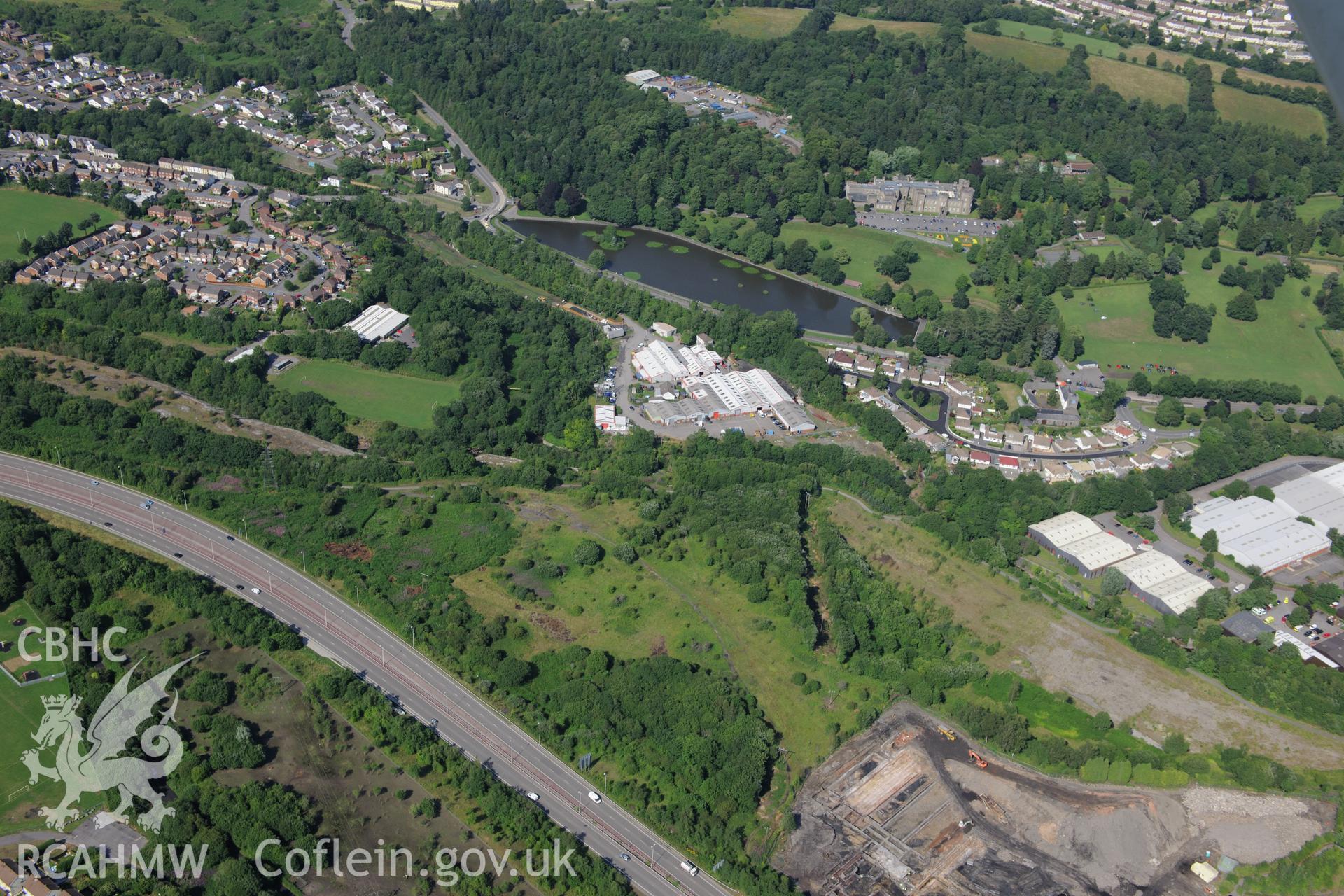 Cyfarthfa Ironworks, remains of blast furnaces, site of former Rotax factory, with Cyfarthfa Castle, School & park beyond. Oblique aerial photograph taken during Royal Commission?s programme of archaeological aerial reconnaissance by Toby Driver 1/08/2013.
