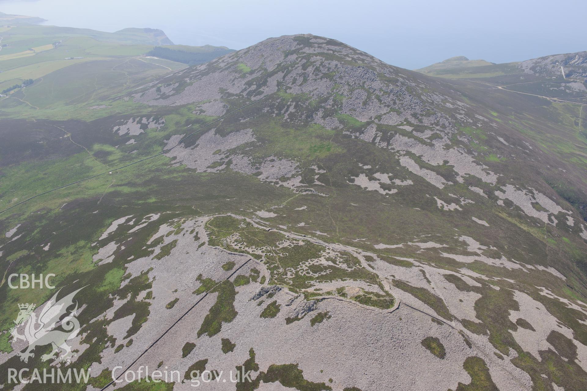 Tre'r Ceiri hillfort with the village of Trefor beyond, on the Lleyn Peninsula. Oblique aerial photograph taken during the Royal Commission?s programme of archaeological aerial reconnaissance by Toby Driver on 12th July 2013.