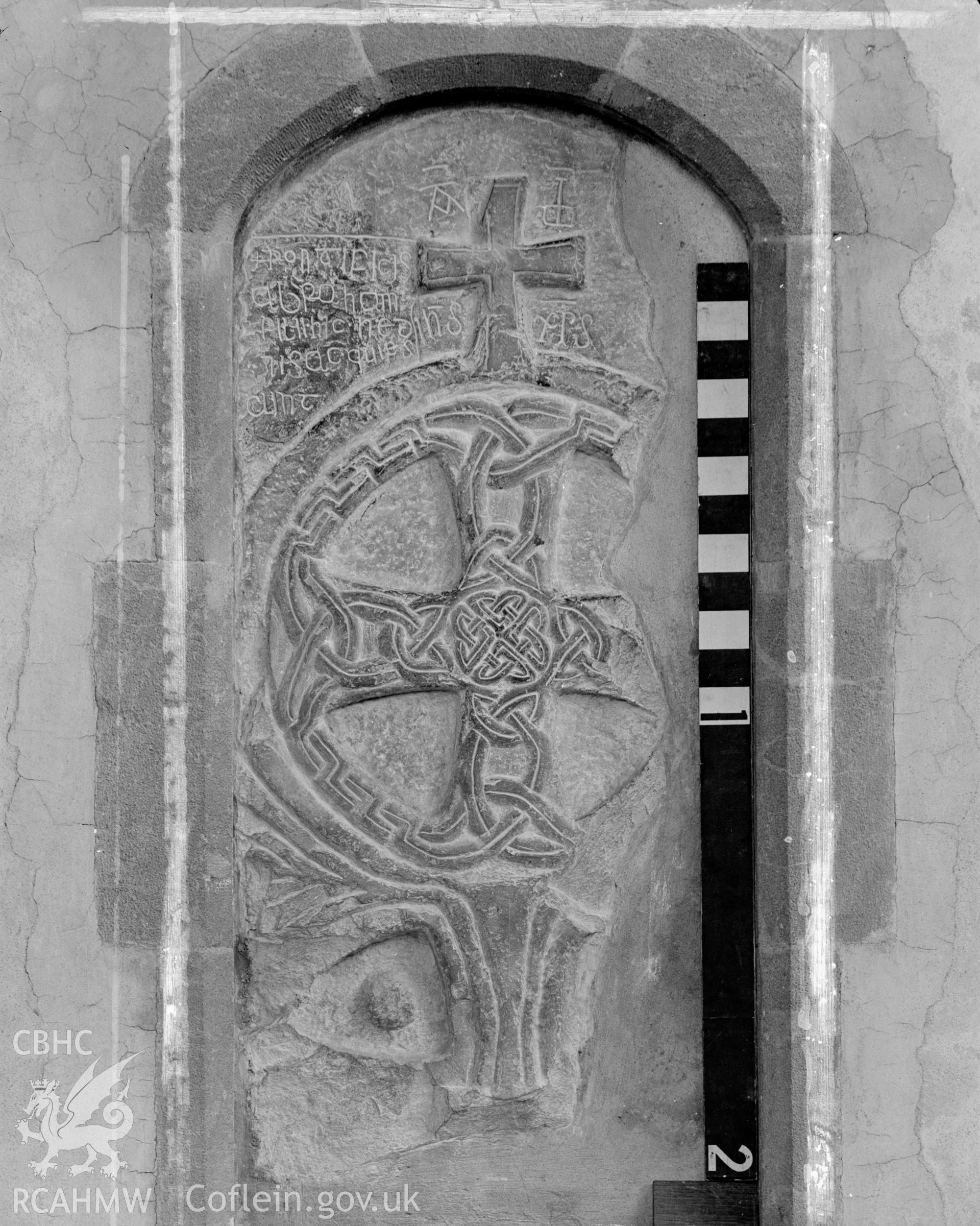 Digital copy of a black and white acetate negative showing view of inscribed stone inserted in archway at St. David's Cathedral, taken by E.W. Lovegrove, July 1936.