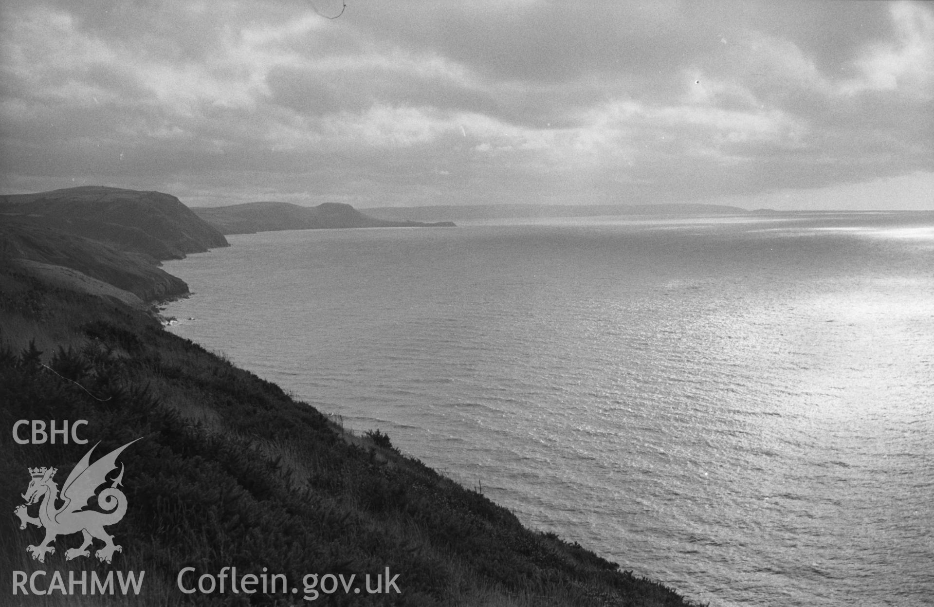 Digital copy of a black and white negative showing view down the coast from Bird's Rock to Penmoelciliau, Pendinas Lochtyn and Cardigan Island. Photographed by Arthur O. Chater in September 1964 from Grid Reference SN 376 600, looking south west.
