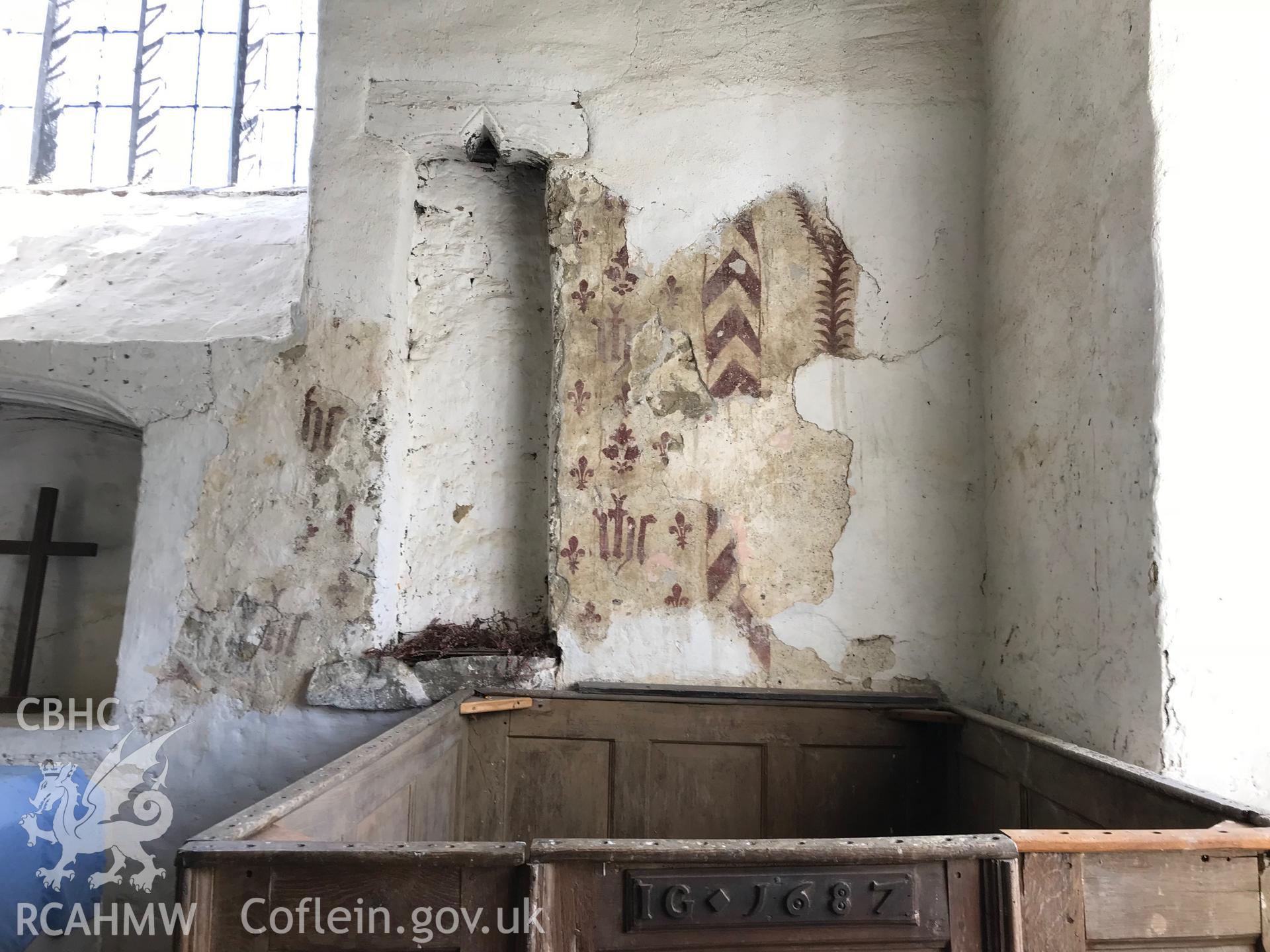 Colour photo showing interior view of St. Cewydd's Church, Diserth, including view of a wooden pew dated 1687, with the initials IG, and fragments of a wall painting, taken by Paul R. Davis, 19th May 2018.