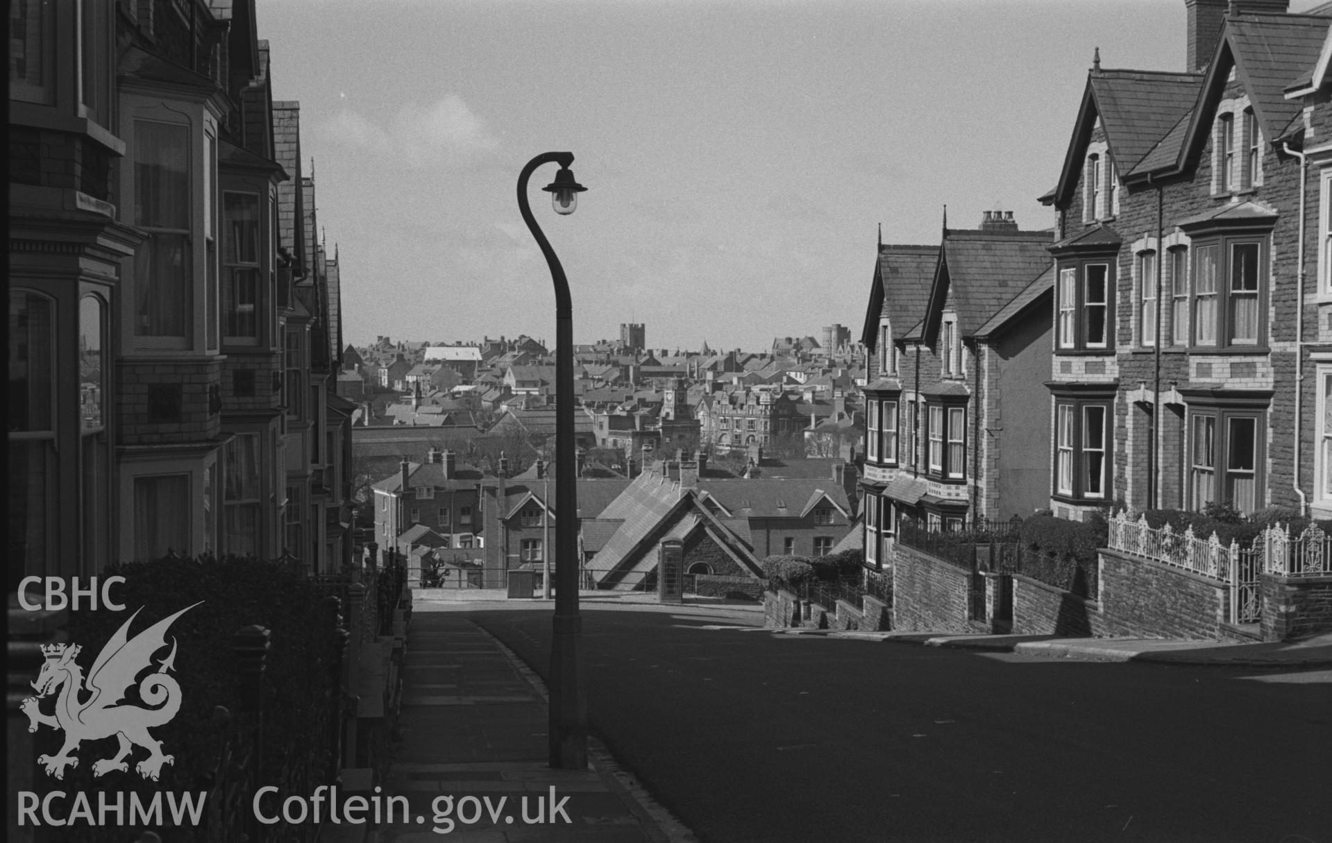 Black and White photograph showing view looking down Buarth Road, across Holy Trinity Church Hall to the tower of St Michaels in the distance, Aberystwyth. Photographed by Arthur Chater in March 1961, from Grid Reference SN 5882 8162.