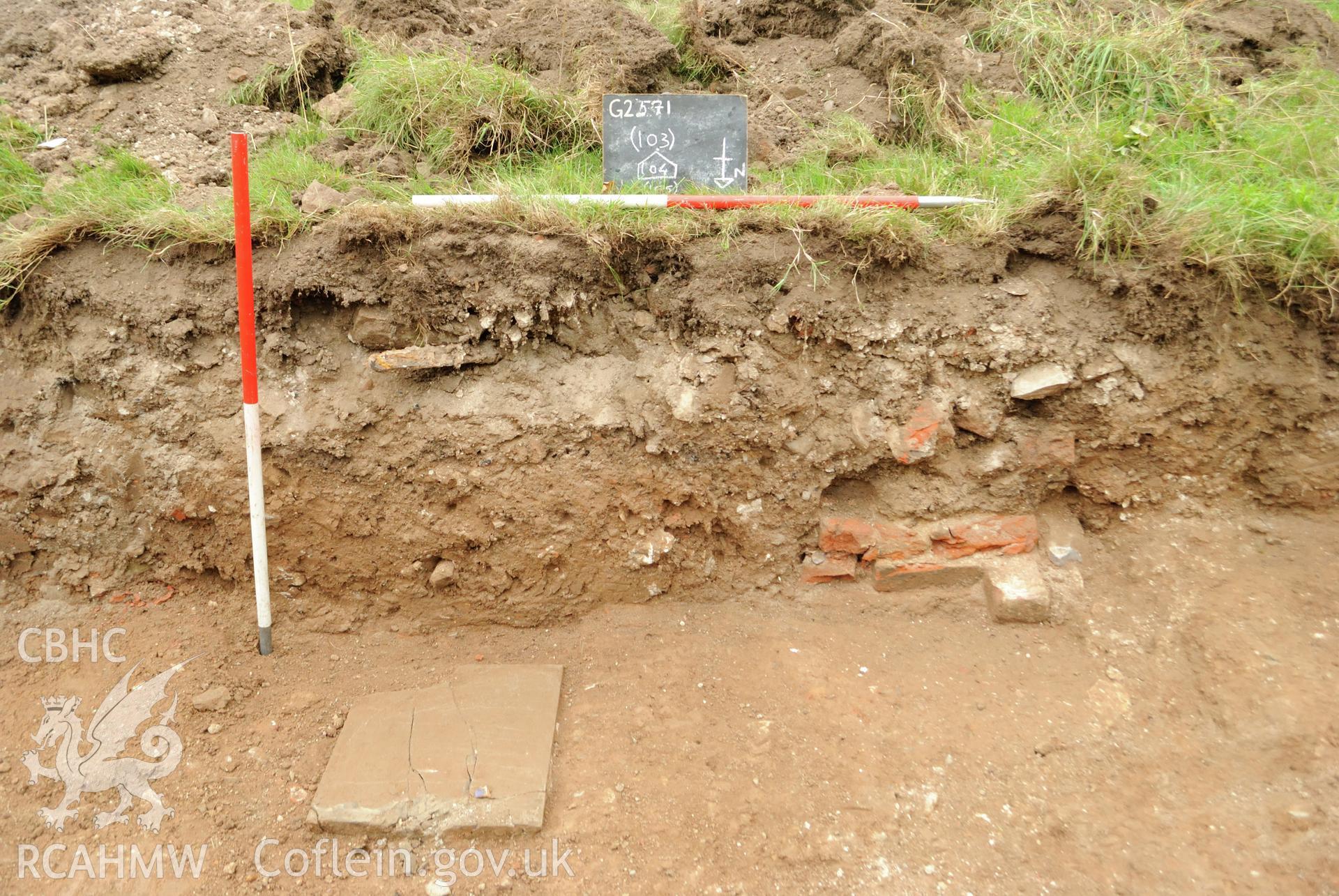 View from the north  of the north facing section in trench 1 with wall fragment 104 and surface 105. Photographed during archaeological evaluation of Kinmel Park, Abergele, conducted by Gwynedd Archaeological Trust on 22nd August 2018. Project no. 2571.