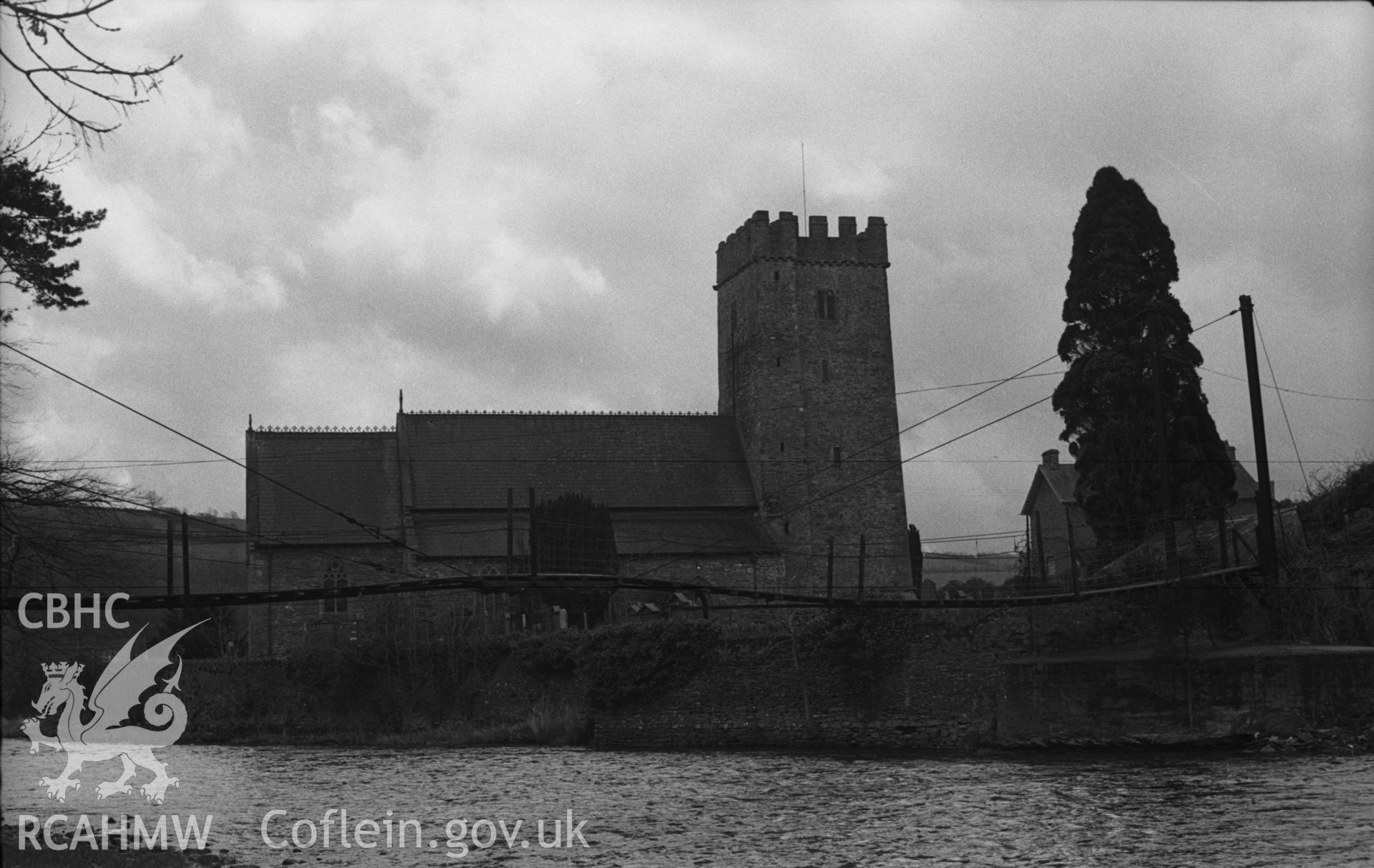 Digital copy of a black and white negative showing exterior view of St Tysul's Church and suspension bridge to Dol-llan at Llandysul. Photographed in April 1963 by Arthur O. Chater from Grid Reference SN 4193 4078, looking south south west.