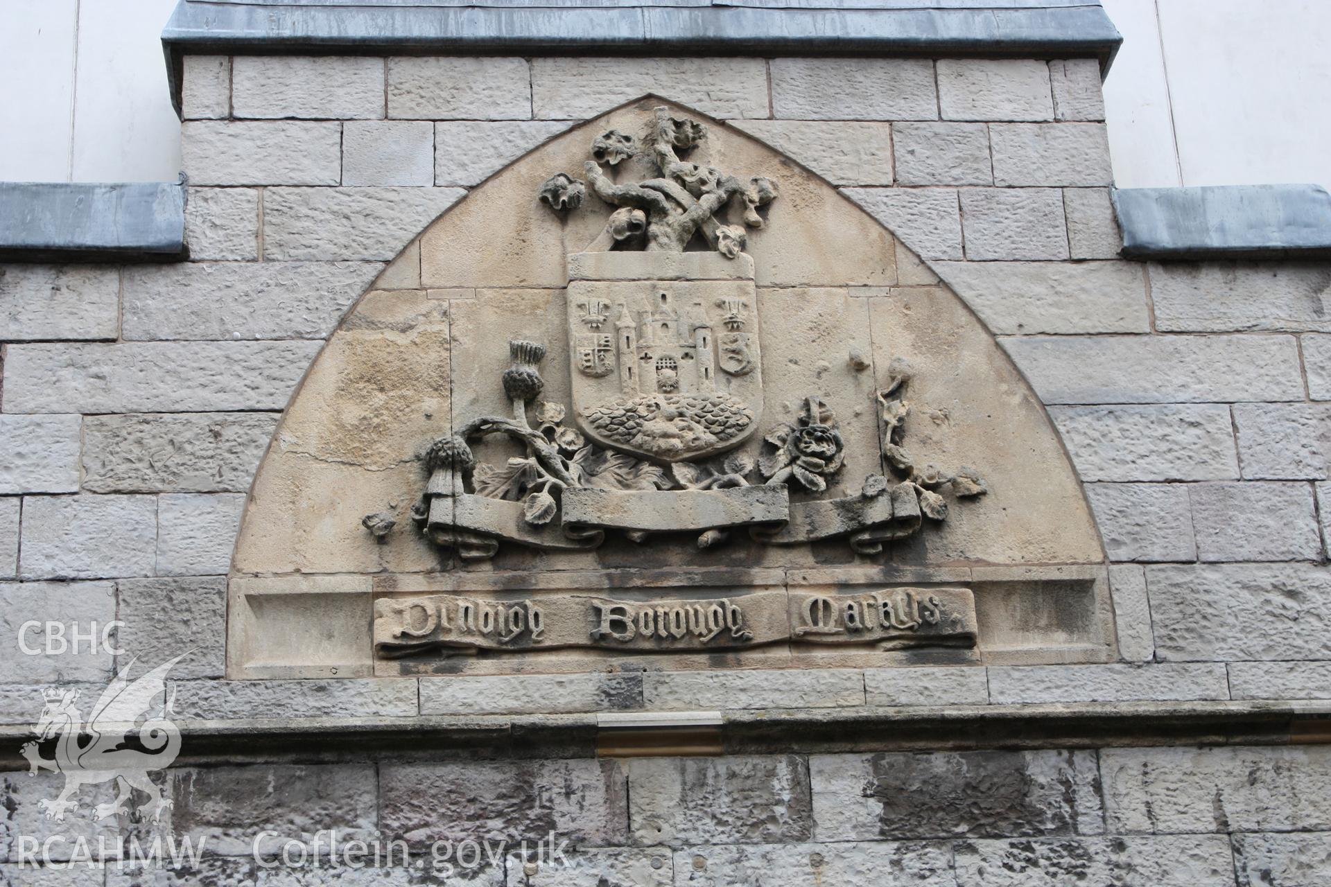 Detail of Denbigh's coat of arms and gothic lettered scroll (reading "Denbigh Borough Markets") carved in relief flush within unmoulded 2-centred arch at Denbigh Borough Market. Colour photograph by Geoff Ward c.2010