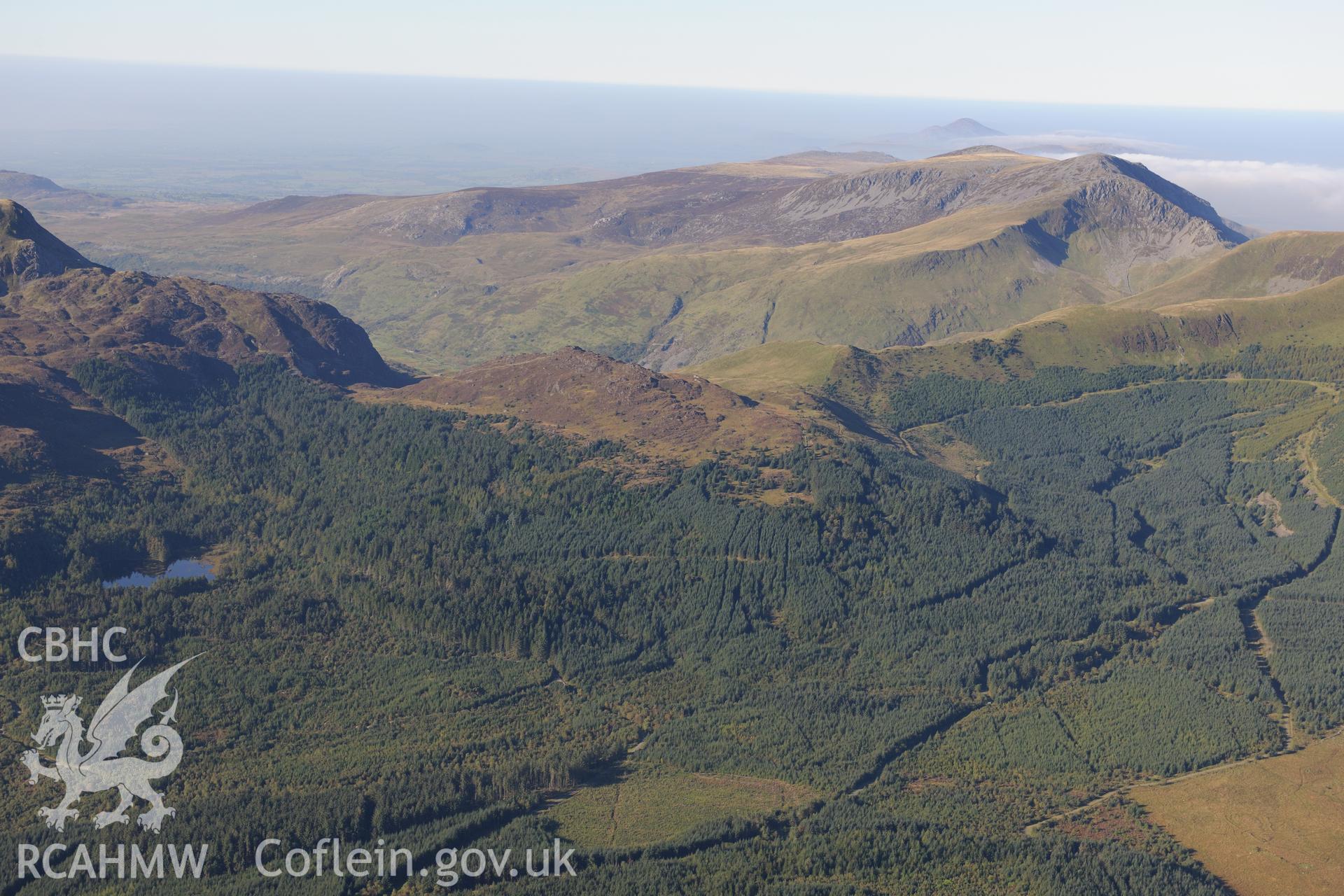 Moel Lefn, surrounded by Beddgelert Forest with Moel Hebog beyond. Oblique aerial photograph taken during the Royal Commission's programme of archaeological aerial reconnaissance by Toby Driver on 2nd October 2015.