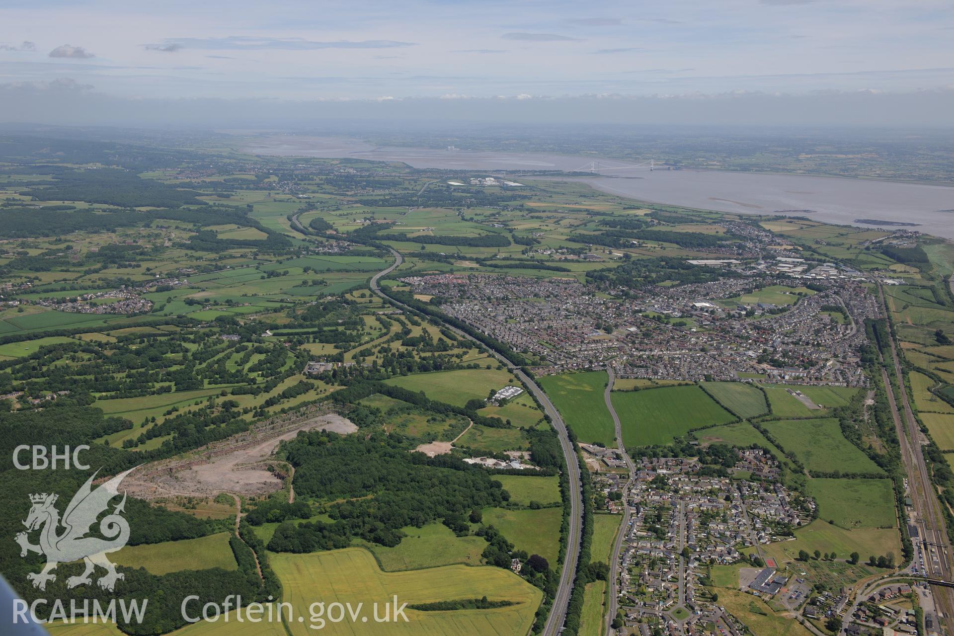 The village of Rogiet and the town of Caldicot beyond, with the M48 motorway to the north and the M4 motorway, the Great Western Railway and the Severn Railway Tunnel to the south. Oblique aerial photograph taken during the Royal Commission's programme of archaeological aerial reconnaissance by Toby Driver on 29th June 2015.