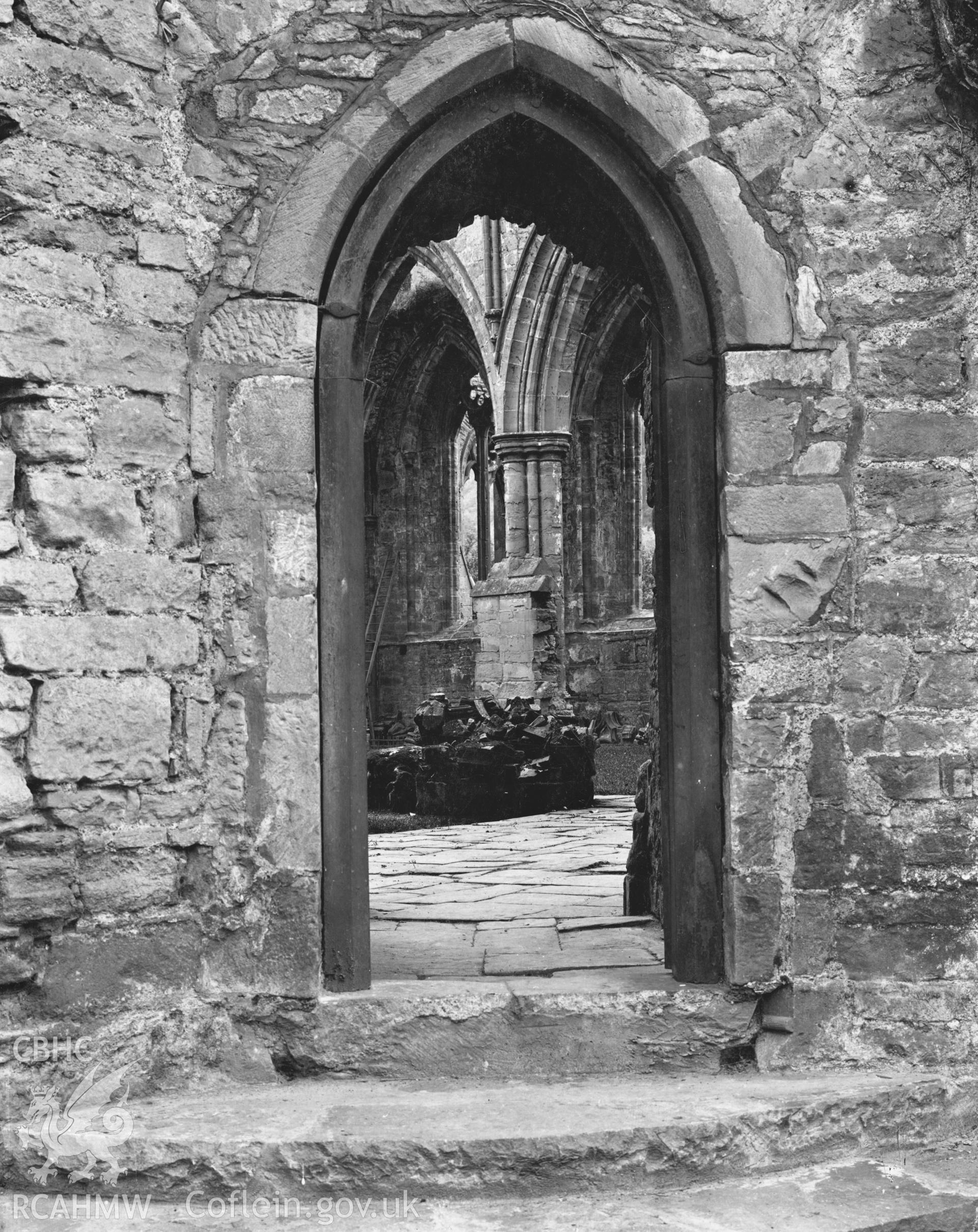 Digital copy of an early National Buildings Record photograph showing doorway from the cloister to the choir at Tintern Abbey.