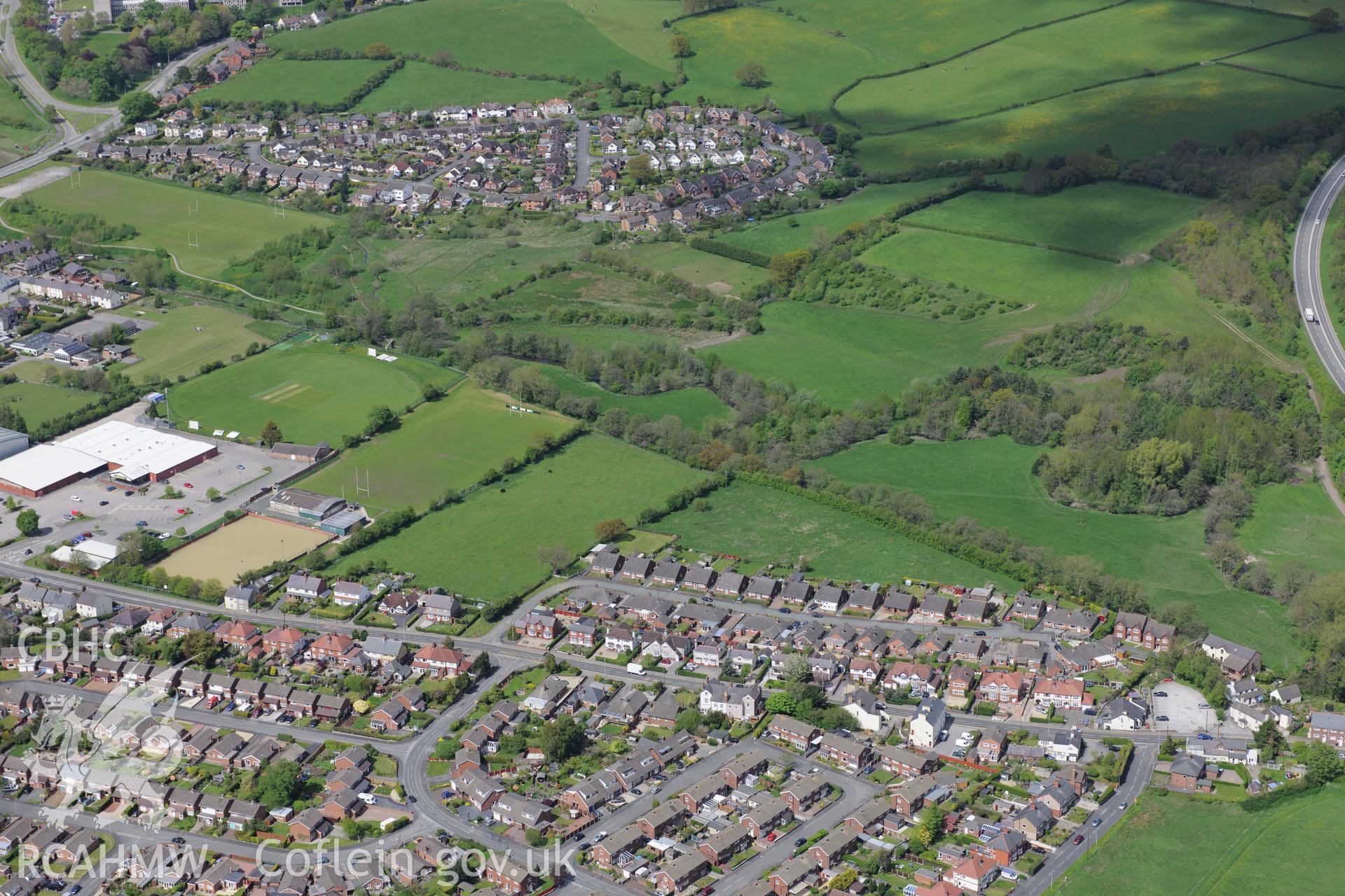 Bryn-yr-Ellyllon Tumulus (findspot of Mold gold cape) and the village of Leadmill, Mold. Oblique aerial photograph taken during the Royal Commission?s programme of archaeological aerial reconnaissance by Toby Driver on 22nd May 2013.