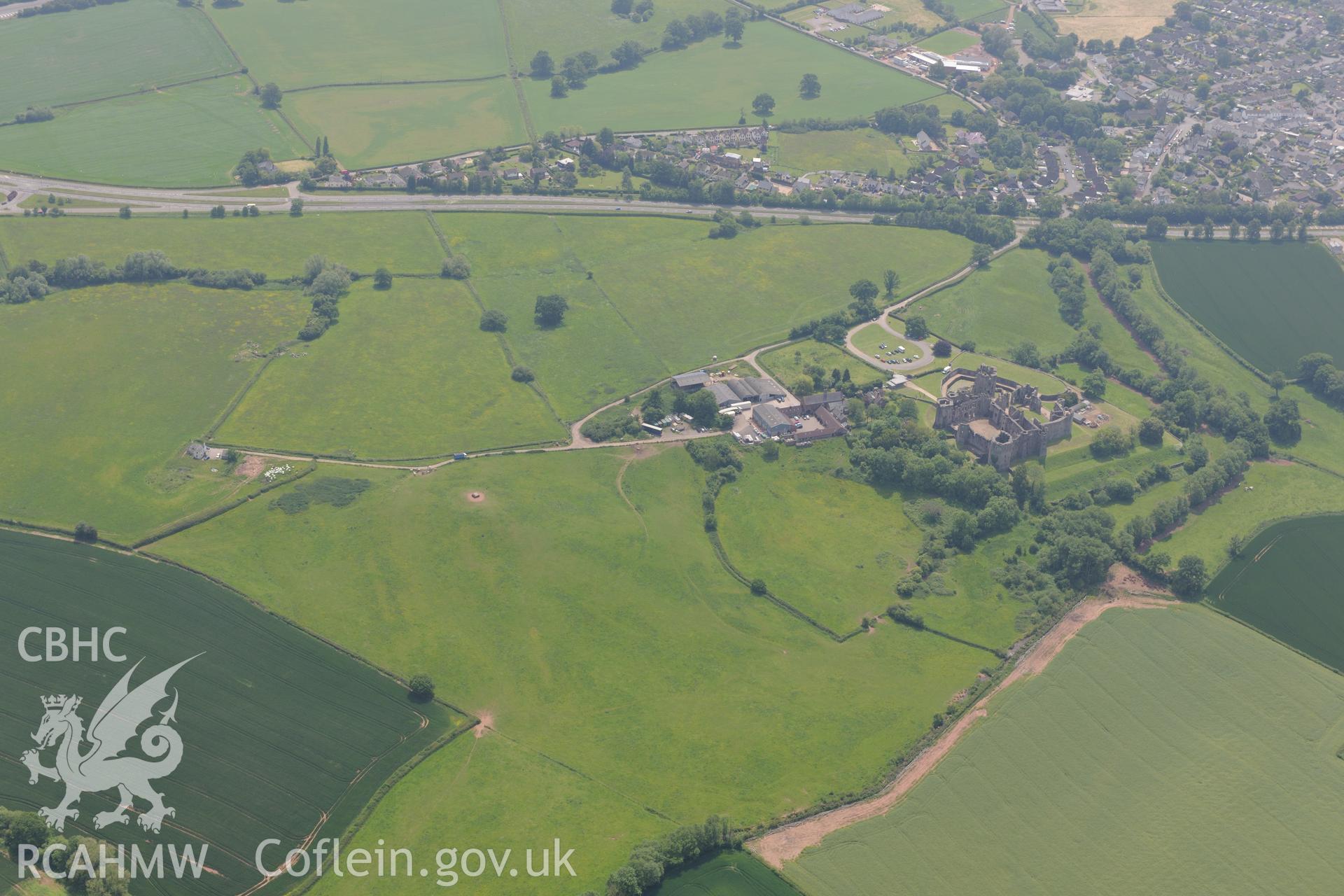 Raglan town including views of Raglan Castle and Castle Farm. Oblique aerial photograph taken during the Royal Commission's programme of archaeological aerial reconnaissance by Toby Driver on 11th June 2015.
