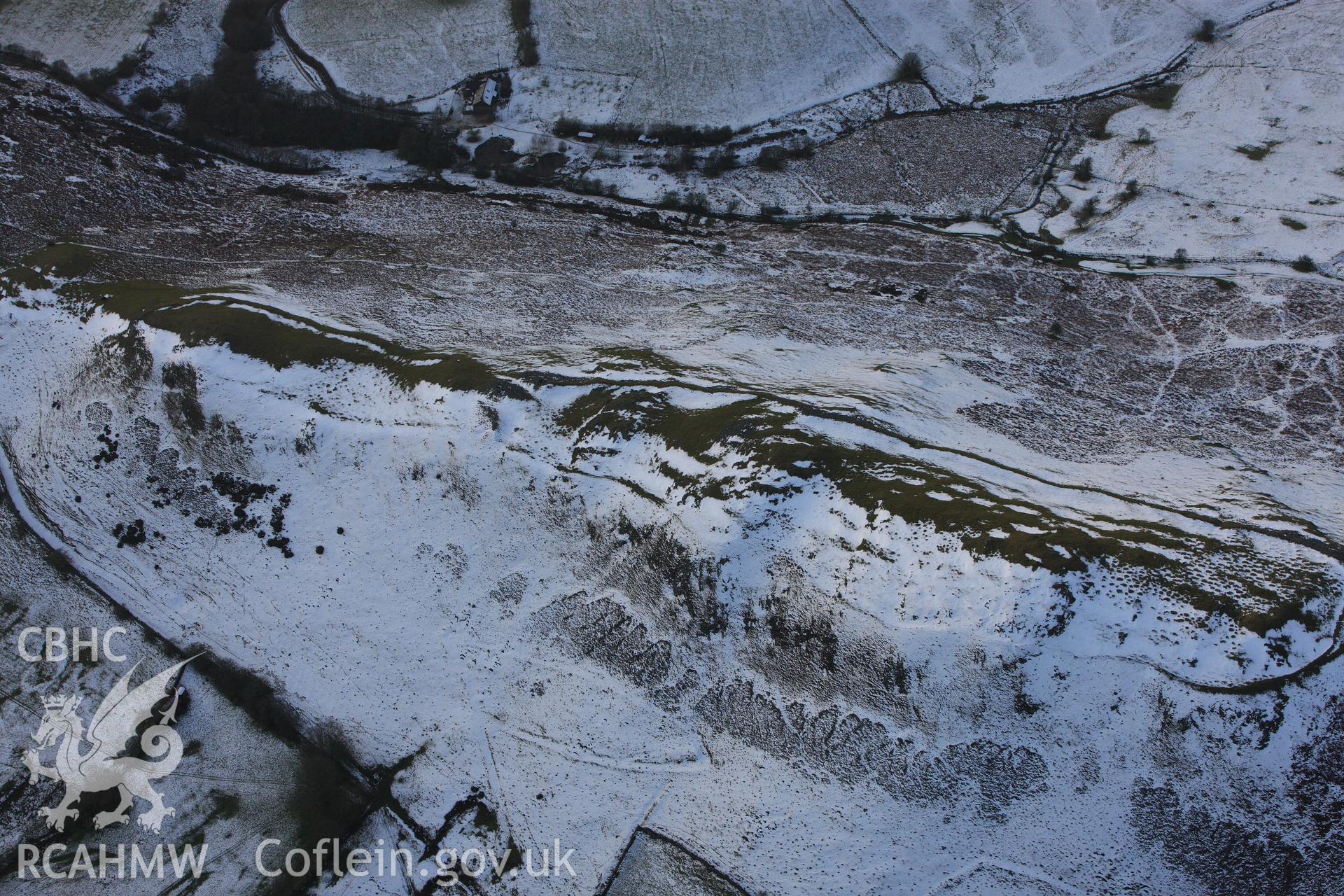 RCAHMW colour oblique photograph of Castle Bank hillfort, with melting snow highlighting defences and house platforms. Taken by Toby Driver on 18/12/2011.