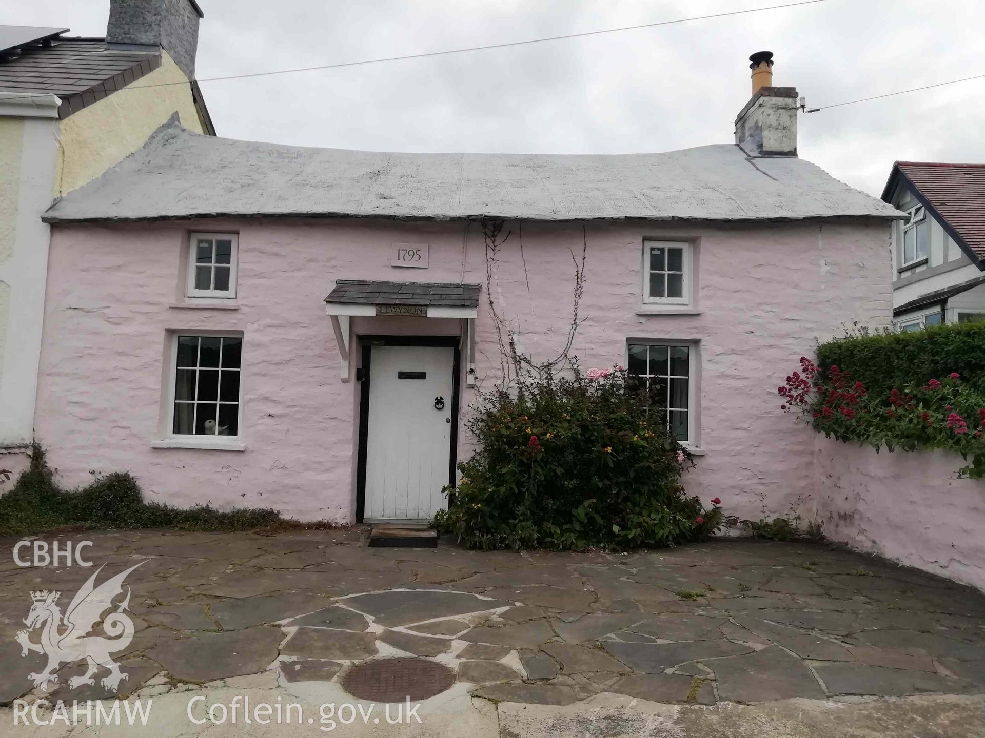 Digital colour photograph showing Llwynon, a traditional fishermans cottage built of stone, overlooking Aberporth beach, with a datestone 1795.