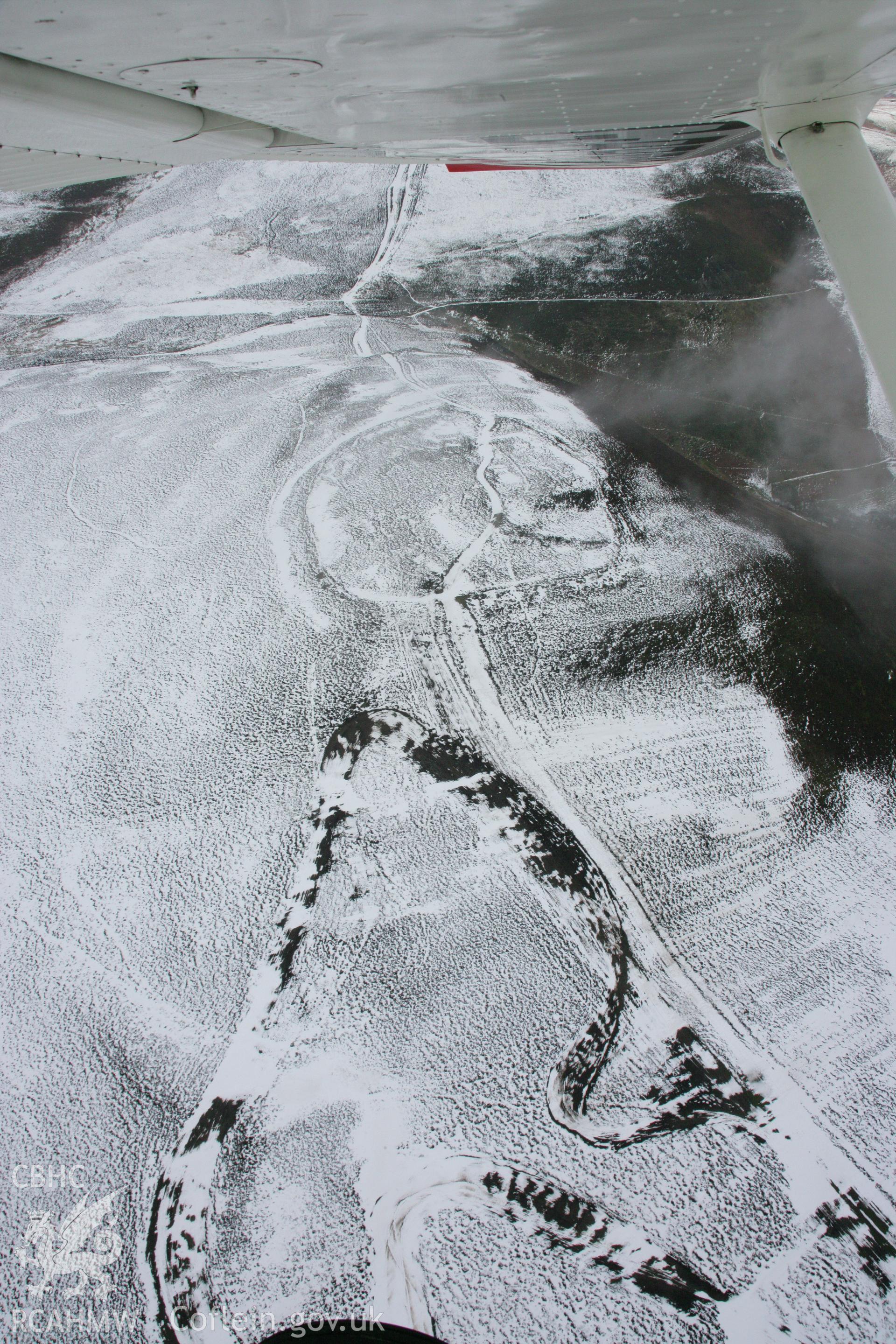 RCAHMW colour oblique aerial photograph of Moel-y-Gaer Hillfort with motorcycle track, Llantysilio, in winter landscape viewed from the south-west. Taken on 06 March 2006 by Toby Driver.