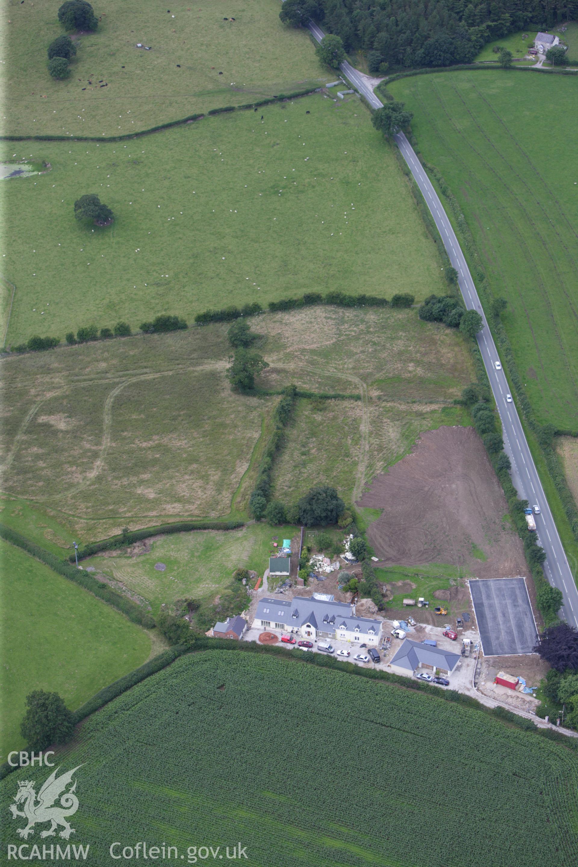 RCAHMW colour oblique aerial photograph of a section of Offa's Dyke, or Whitford Dyke, northwest and southeast of Brynbella Mound. Building work is visible nearby. Taken on 30 July 2009 by Toby Driver