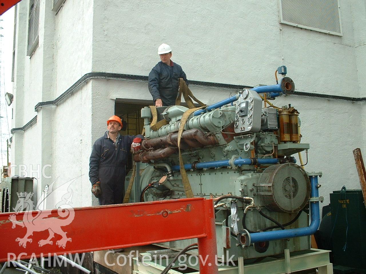 Colour digital photograph showing an engine being moved onto a truck.