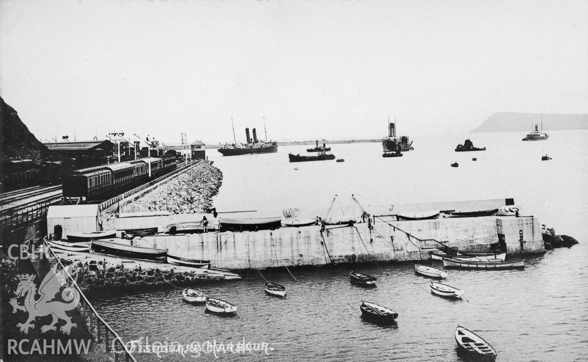 Fishguard Harbour; undated  black and white picture postcard showing view of the original harbour wall and slipway which served the nearrby coastguard station (the railway company ferry with two funnels is visible in the background).