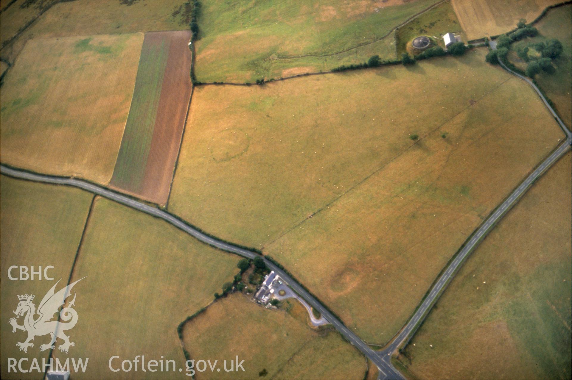 RCAHMW colour slide oblique aerial photograph of Caerlan Tibot defended enclosure, Caernarfon, taken by C.R.Musson, 1990.
