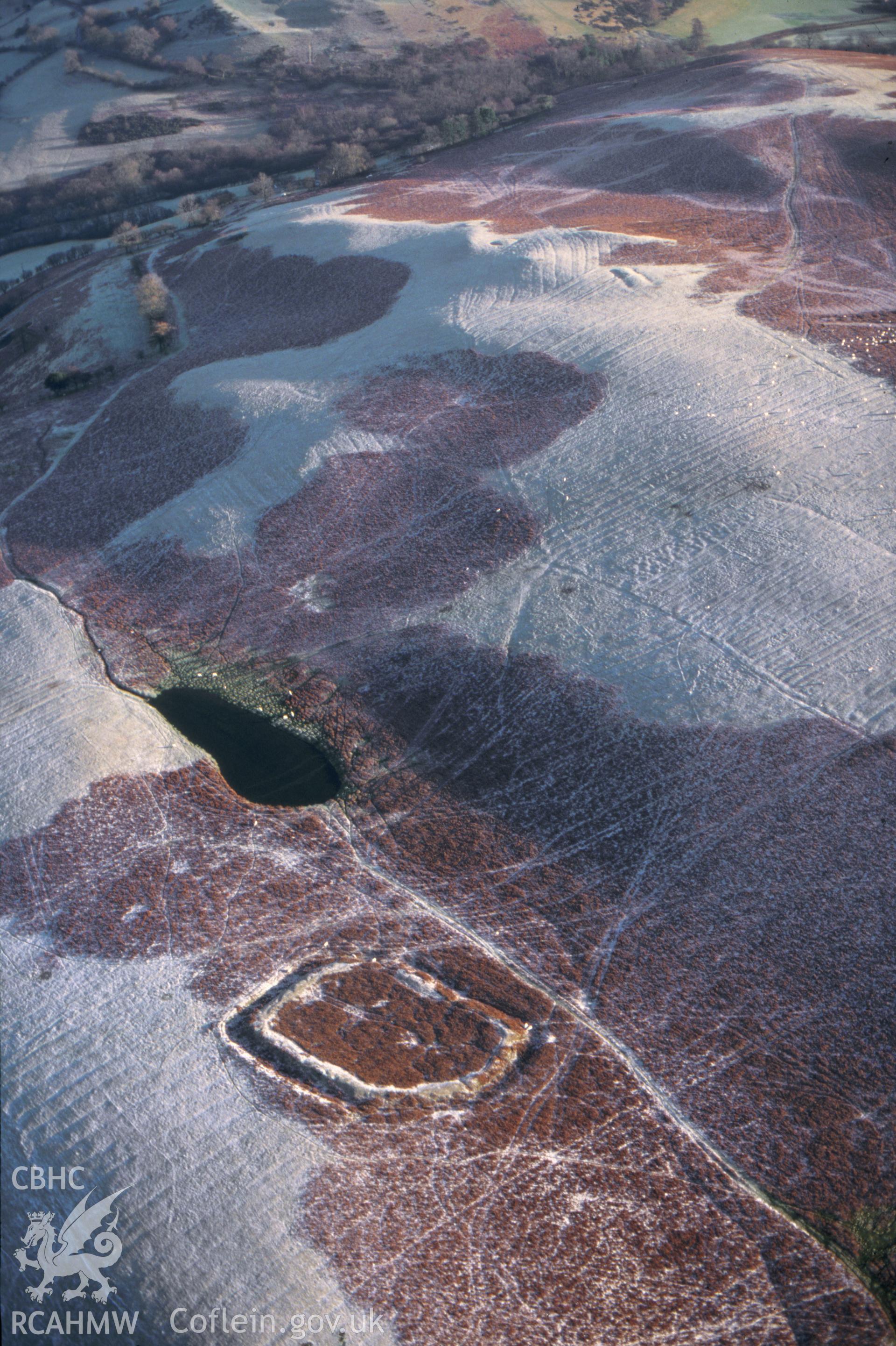RCAHMW colour slide oblique aerial photograph of Coed Swydd Enclosure, Penybont, taken on 09/01/1999 by CR Musson