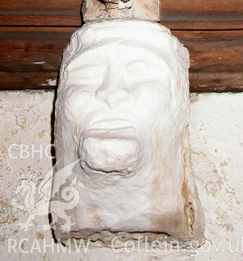 Carved stone head between Trusses III & IV, south side.