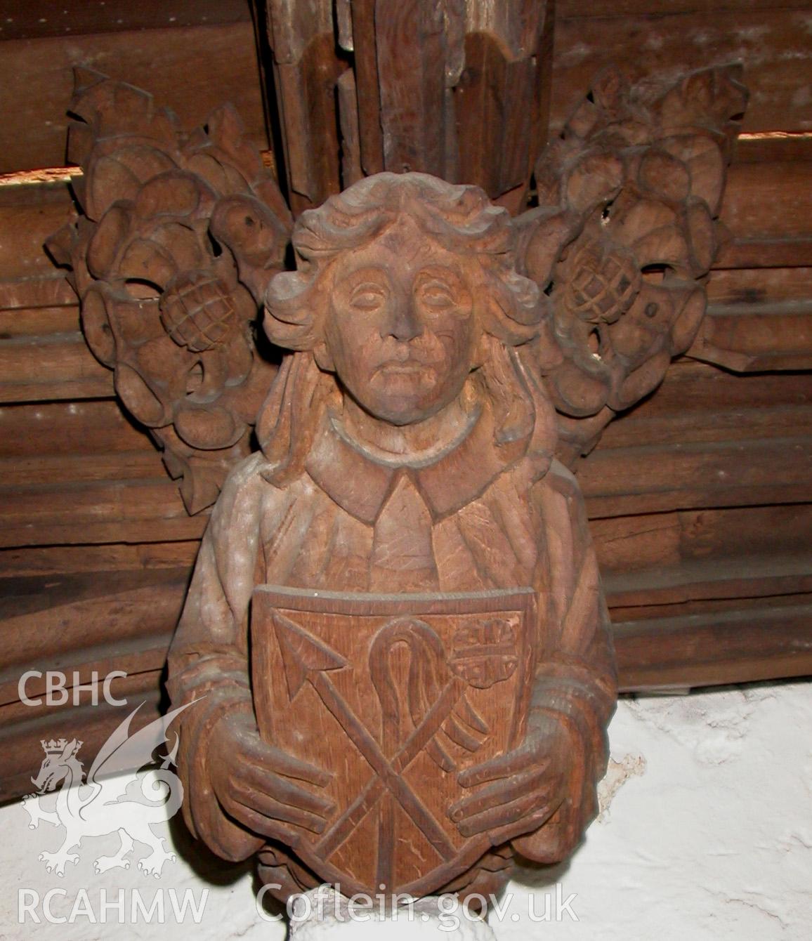 Carved wooden head at east end, to North.