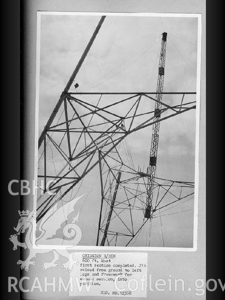 Black and white digital photograph of a 600 ft mast with the first section completed. The framework for the second section has been put into position.