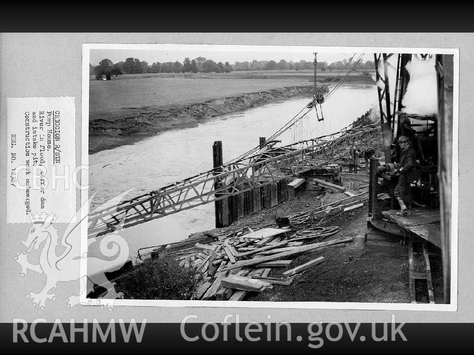 Black and white digital photograph of the river in flood, the coffer dam and the intake pit. The construction work is submerged.