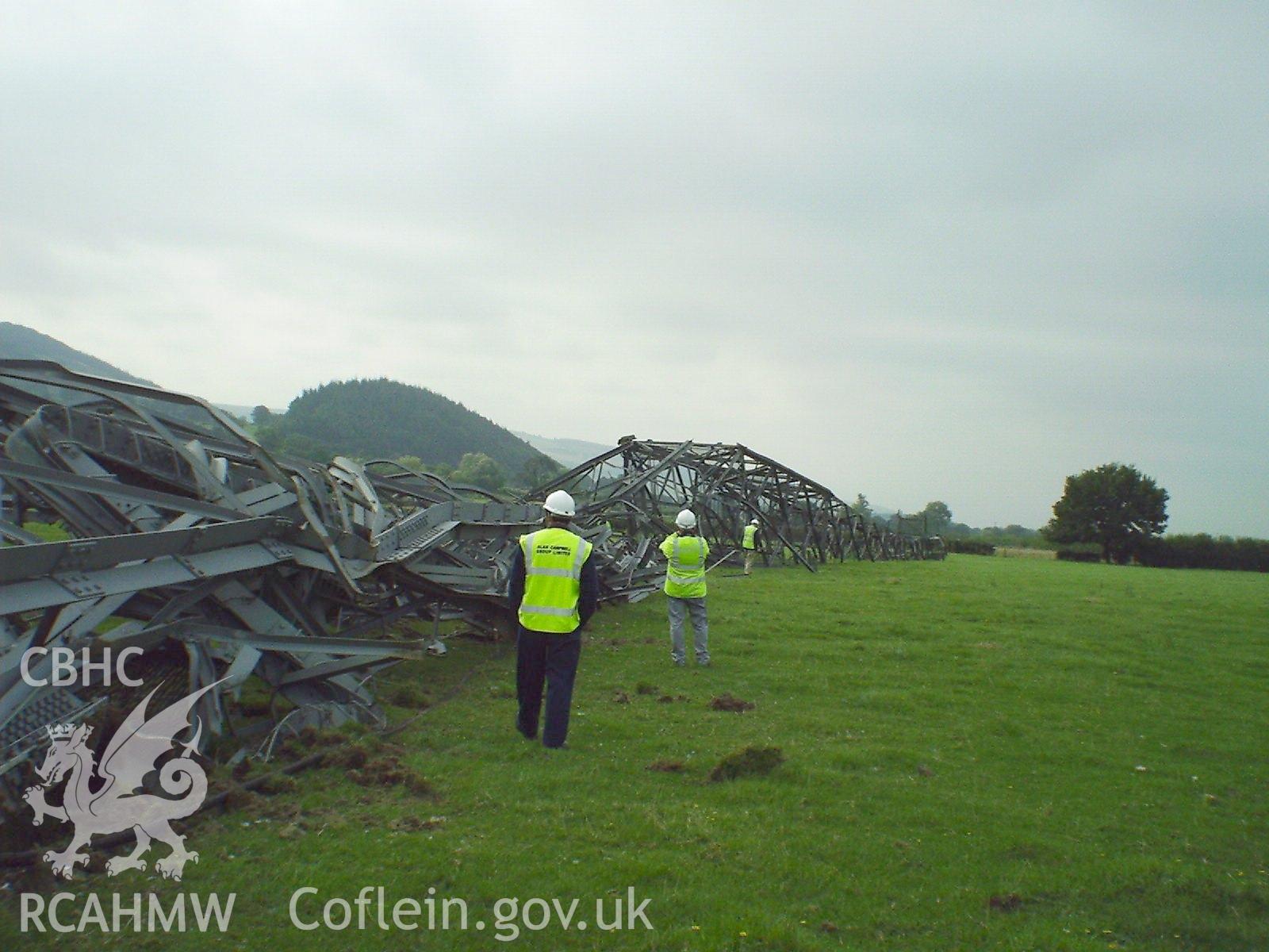 Colour digital photograph of workmen inspecting a demolished tower.