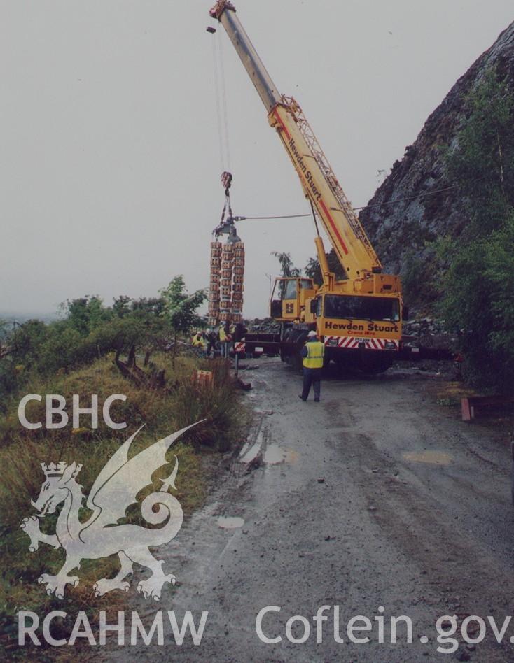 Colour digital photograph of a crane lifting some machinery.